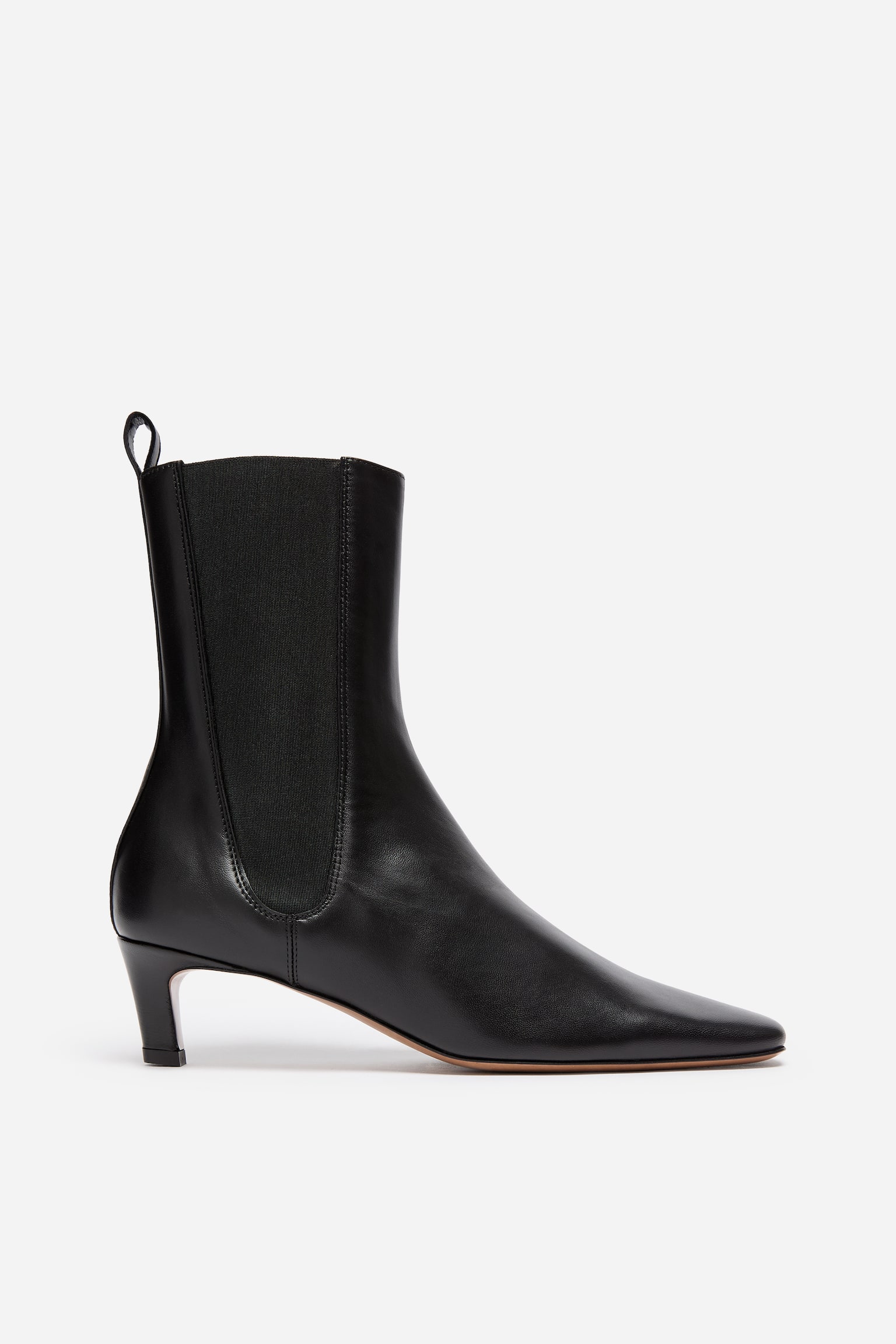 En sort ankelstÃ¸vle i lÃ¦der vender mod hÃ¸jre og har en spids firkantet tÃ¥, en lav kitten heel og et hÃ¸jt skaft. StÃ¸vlen har en bred elastisk sidekile og en lÃ¦dertrÃ¦kstrop pÃ¥ den bagerste krave.