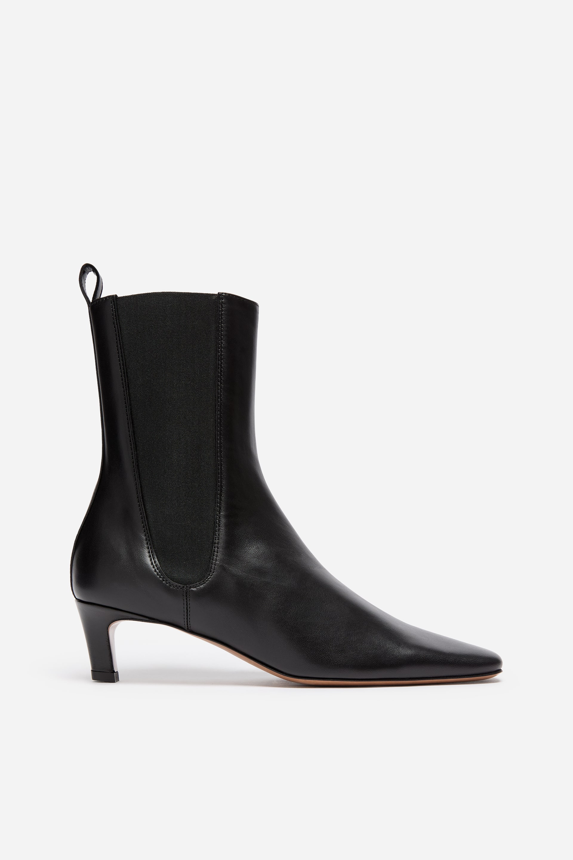 Grösseres Bild ansehen: Ein schwarzer Lederstiefeletten ist nach rechts ausgerichtet und verfügt über eine schmal zulaufende eckige Spitze, einen niedrigen Kitten-Heel und einen hohen Schaft. Der Stiefel zeigt einen breiten elastischen Seiteneinsatz sowie eine Lederschlaufe an der hinteren Schaftrand.