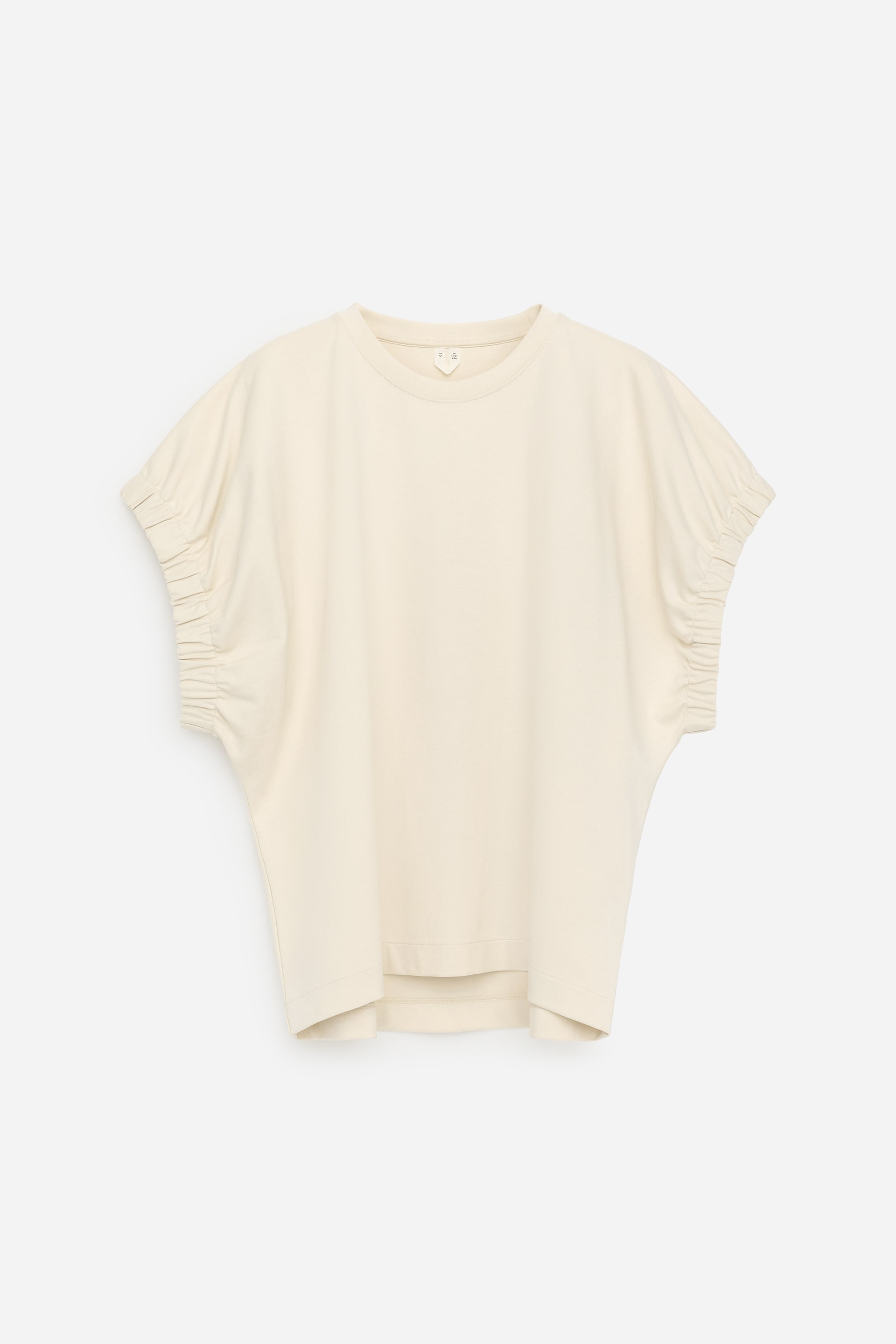 Vezi imaginea mai mare: Un tricou crem este prezentat din față, având o croială lejeră și un guler rotund. Mânecile scurte sunt decorate cu detalii adunate și manșete elastice.