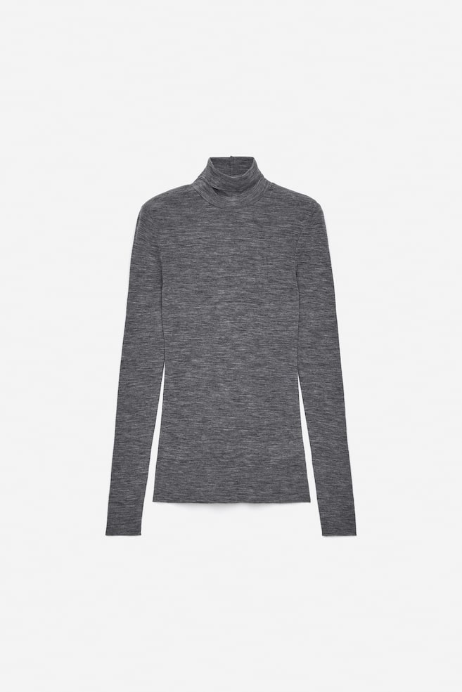 Un top de cuello alto tejido en un gris oscuro jaspeado se presenta desde el FRENTE. Presenta mangas largas y bordes sin rematar en los puños, el cuello y el dobladillo inferior. - 1