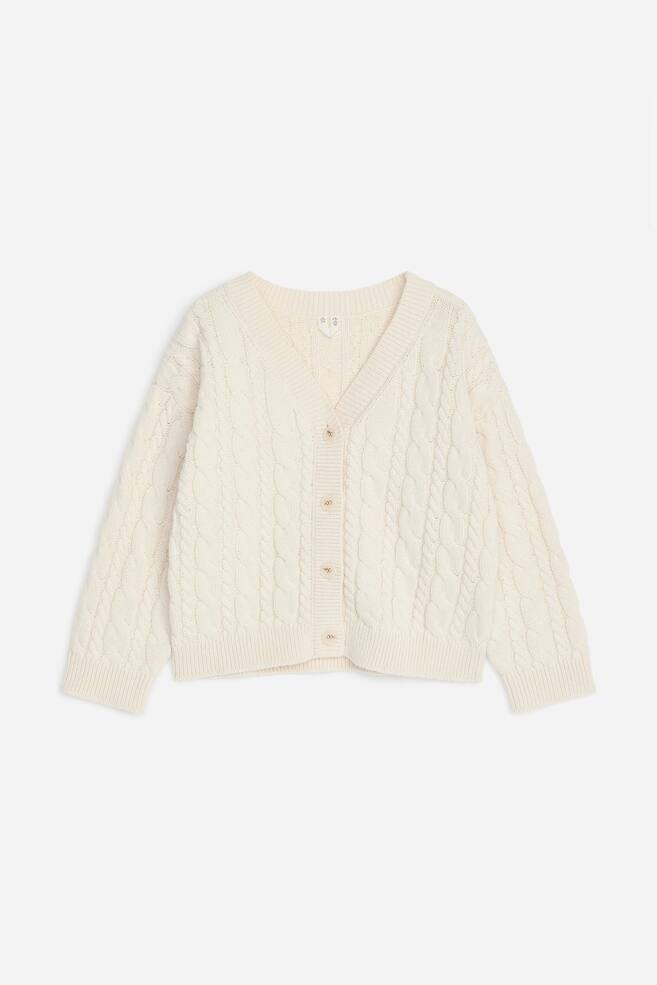 ÎÎ½Î± ÏÏÏÎ»ÎµÏÎºÎ¿ ÏÎ»ÎµÎºÏÏ Î¶Î±ÎºÎµÏÎ¬ÎºÎ¹ Î¼Îµ ÏÎ»Î­Î¾Î· cable-knit ÏÎ±ÏÎ¿ÏÏÎ¹Î¬Î¶ÎµÏÎ±Î¹ Î±ÏÏ Î¼ÏÏÎ¿ÏÏÎ¬, Î¼Îµ Î²Î±Î¸Ï V Î½ÏÎµÎºÎ¿Î»ÏÎ­ ÎºÎ±Î¹ Î¼ÏÏÎ¿ÏÏÎ¹Î½Ï ÎºÎ»ÎµÎ¯ÏÎ¹Î¼Î¿ Î¼Îµ ÎºÎ¿ÏÎ¼ÏÎ¹Î¬ ÎºÎ±Î¹ ÏÎ­ÏÏÎµÏÎ± Î¼Î¹ÎºÏÎ¬ ÎºÎ¿ÏÎ¼ÏÎ¹Î¬. Î¤Î± Î¼Î±ÎºÏÎ¹Î¬ Î¼Î±Î½Î¯ÎºÎ¹Î±, Î¿Î¹ Î¼Î±Î½ÏÎ­ÏÎµÏ ÎºÎ±Î¹ ÏÎ¿ ÏÎµÎ»ÎµÎ¯ÏÎ¼Î± Î¿Î»Î¿ÎºÎ»Î·ÏÏÎ½Î¿Î½ÏÎ±Î¹ Î¼Îµ ÏÎ¹Î¼Ï Î»ÎµÏÏÎ¿Î¼Î­ÏÎµÎ¹ÎµÏ, Î±Î½Î±Î´ÎµÎ¹ÎºÎ½ÏÎ¿Î½ÏÎ±Ï ÏÎµ ÏÎ»Î· ÏÎ·Î½ ÎµÏÎ¹ÏÎ¬Î½ÎµÎ¹Î± ÏÎ¿ Î±Î½Î¬Î³Î»ÏÏÎ¿ ÏÎ»ÎµÎºÏÏ Î¼Î¿ÏÎ¯Î²Î¿. - 1