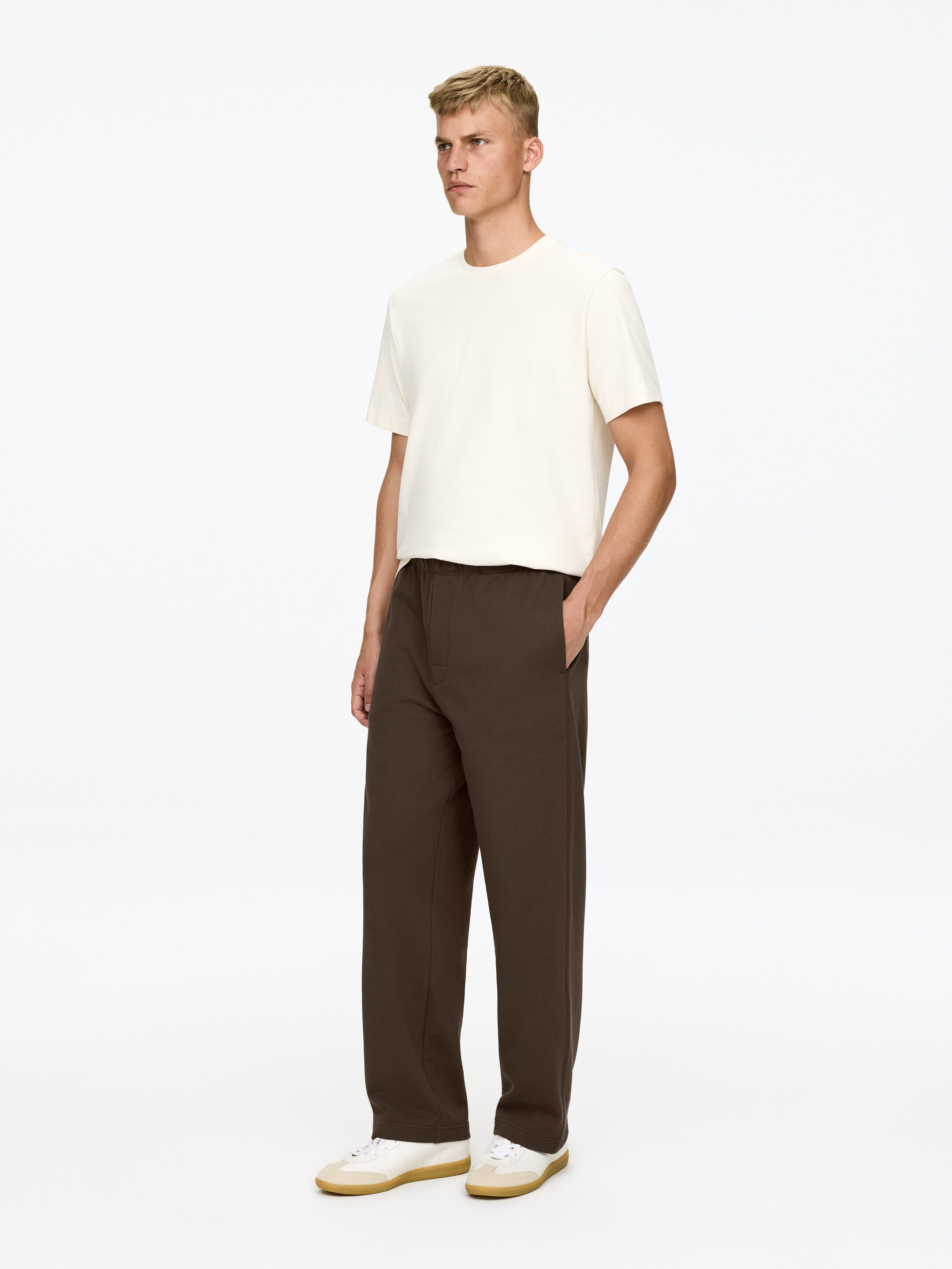 Ingrandisci l'immagine: Un paio di pantaloni marrone scuro a vestibilità comoda viene presentato da un'angolazione frontale, caratterizzati da una fascia elastica in vita, gambe dritte e tasche laterali.