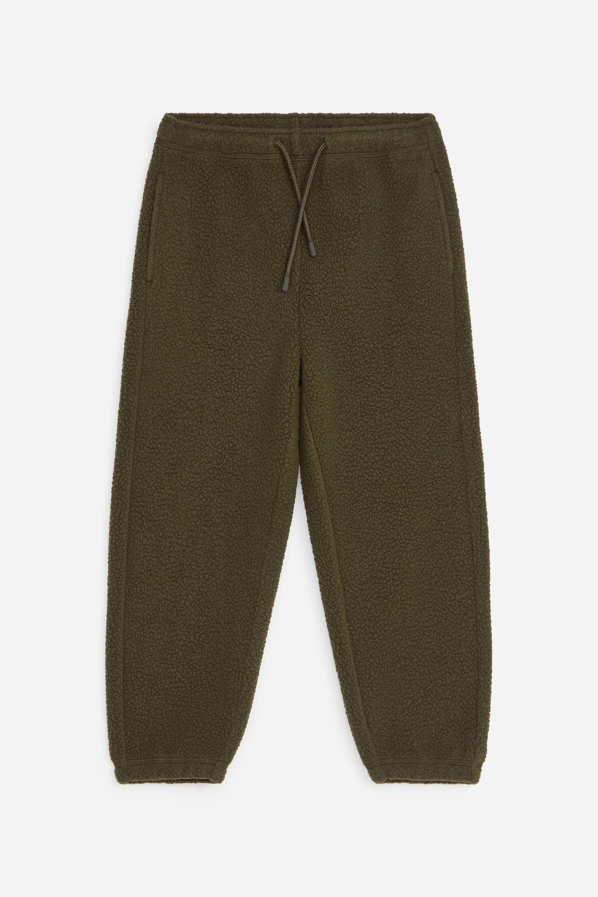 View larger image: A pair of olive green sherpa fleece sweatpants is shown from the front, featuring an elasticated waistband with an adjustable drawstring. The sweatpants display a textured, high-pile finish, side seam pockets, and tapered legs ending in elasticated cuffs.