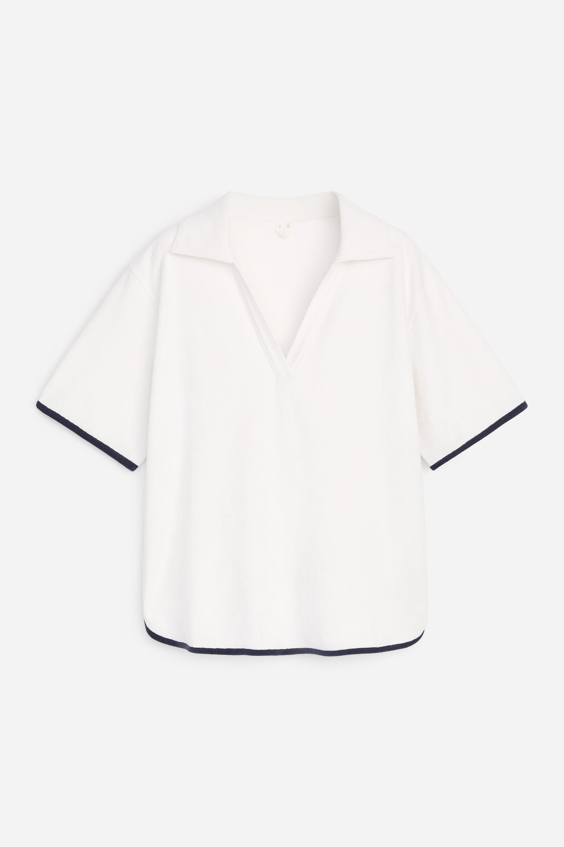 View larger image: A white, relaxed-fit top is showcased at the front, featuring a subtle towelling texture. It is designed with a V-neckline, a spread collar, and short sleeves, with navy blue piping trimming the sleeve cuffs and bottom hem.