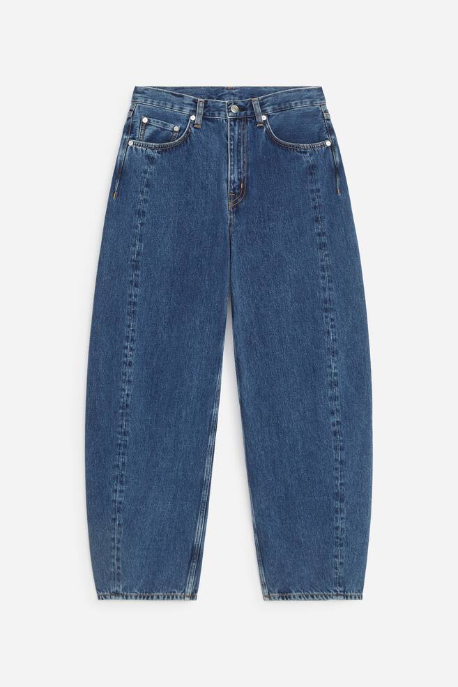 Diese blau gewaschenen Denim-Jeans sind von vorne zu sehen und zeigen einen mittelhohen Bund mit klassischem Five-Pocket-Design und ReiÃverschluss. Die Jeans haben eine lockere Passform mit geformten, geschwungenen Beinen und vertikalen NÃ¤hten, die vorne nach unten verlaufen. - 1