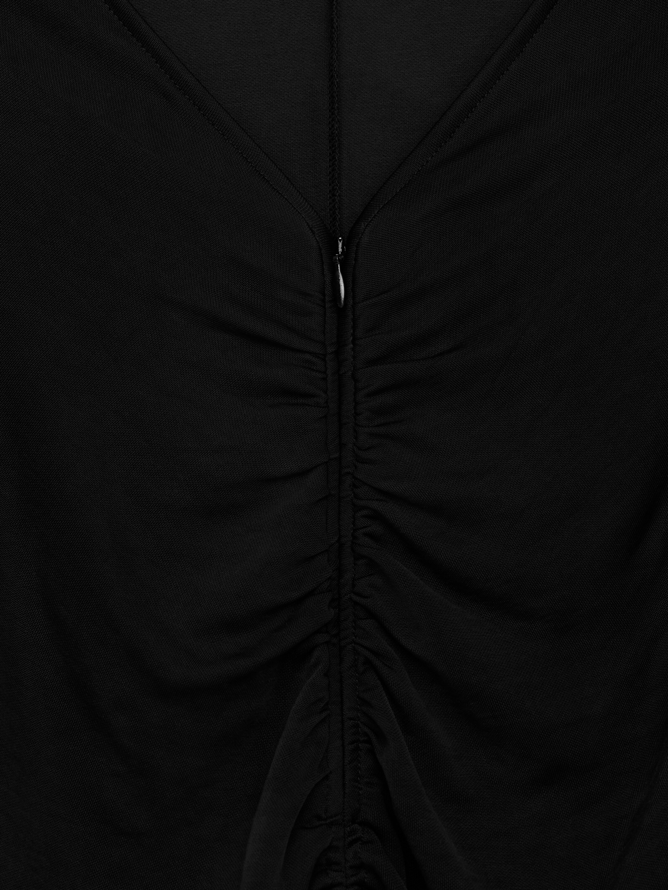 View larger image: A black garment is displaying a V-neckline at the top, leading into a central vertical ruching detail. A silver zipper pull is partially visible, integrated into the ruched fabric along the front.