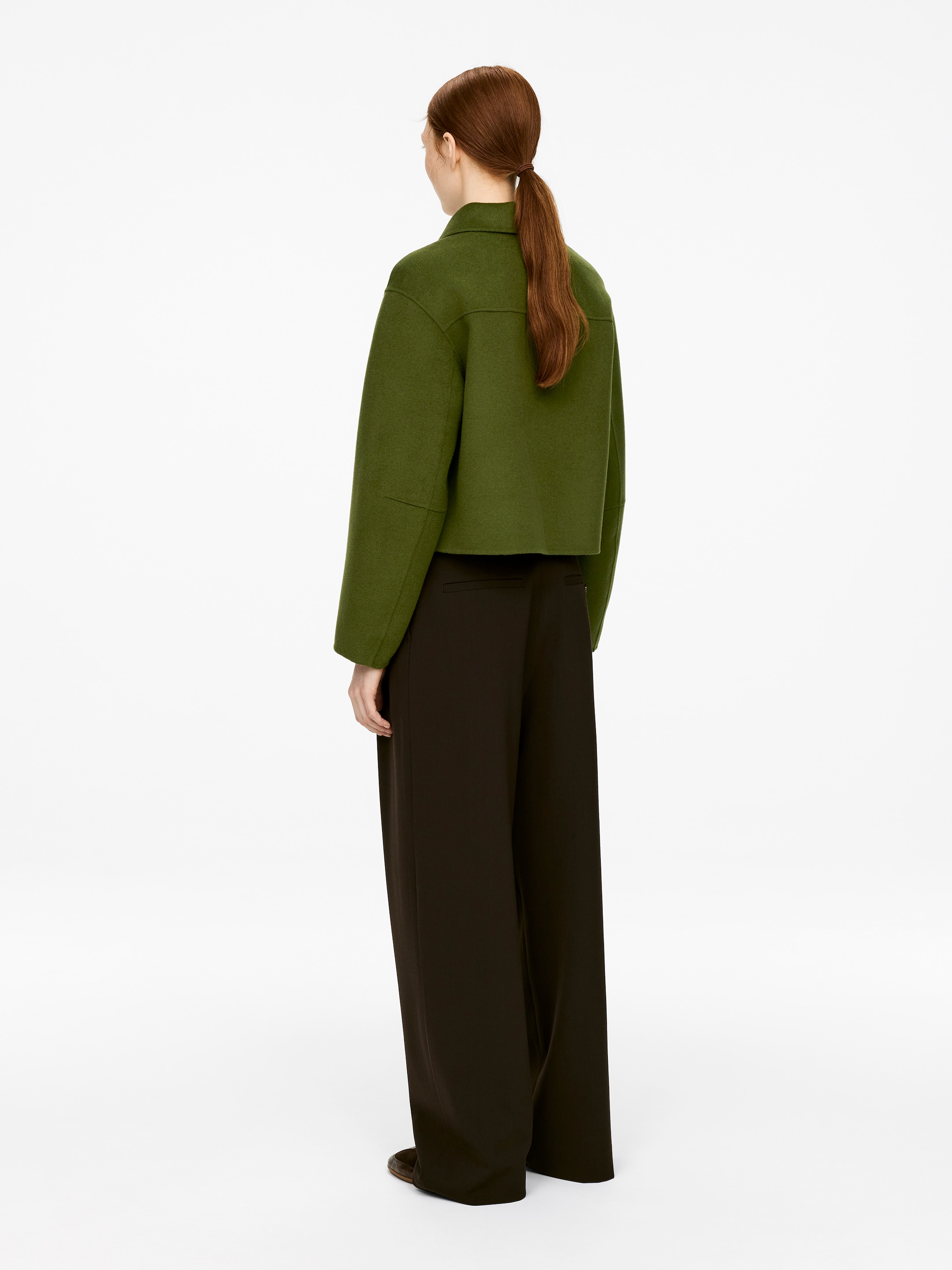 Ver imagen más grande: Una sobrecamisa con cuello verde, con un ajuste regular y detalles de costura visibles en la parte trasera, está siendo usada por el modelo. Está confeccionada con una tela de mezcla de lana y se coloca sobre unos pantalones oscuros de pierna ancha.