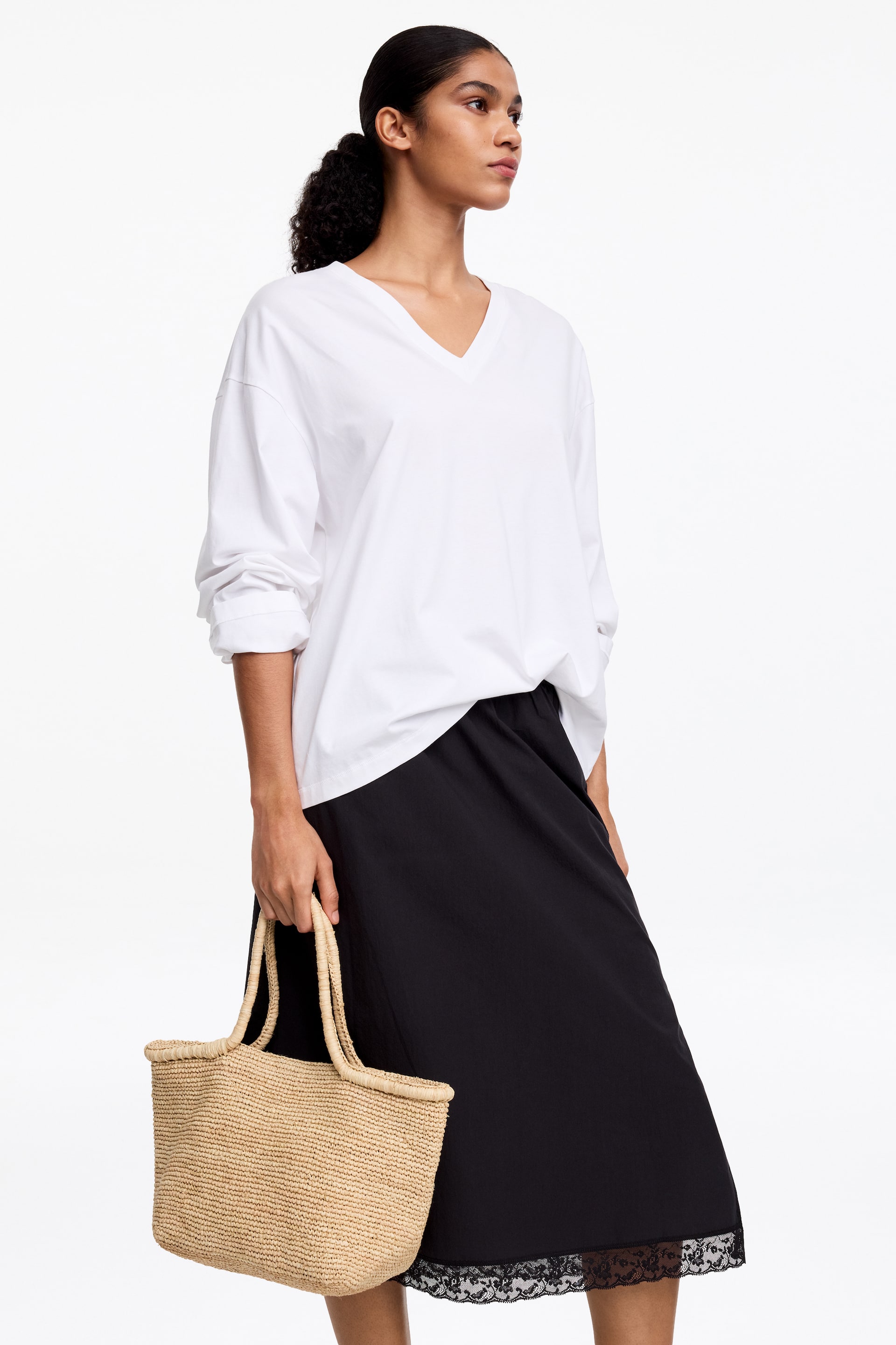 View larger image: The white V-neck long-sleeve top features a relaxed, oversized fit, with its long sleeves rolled up at the forearms.