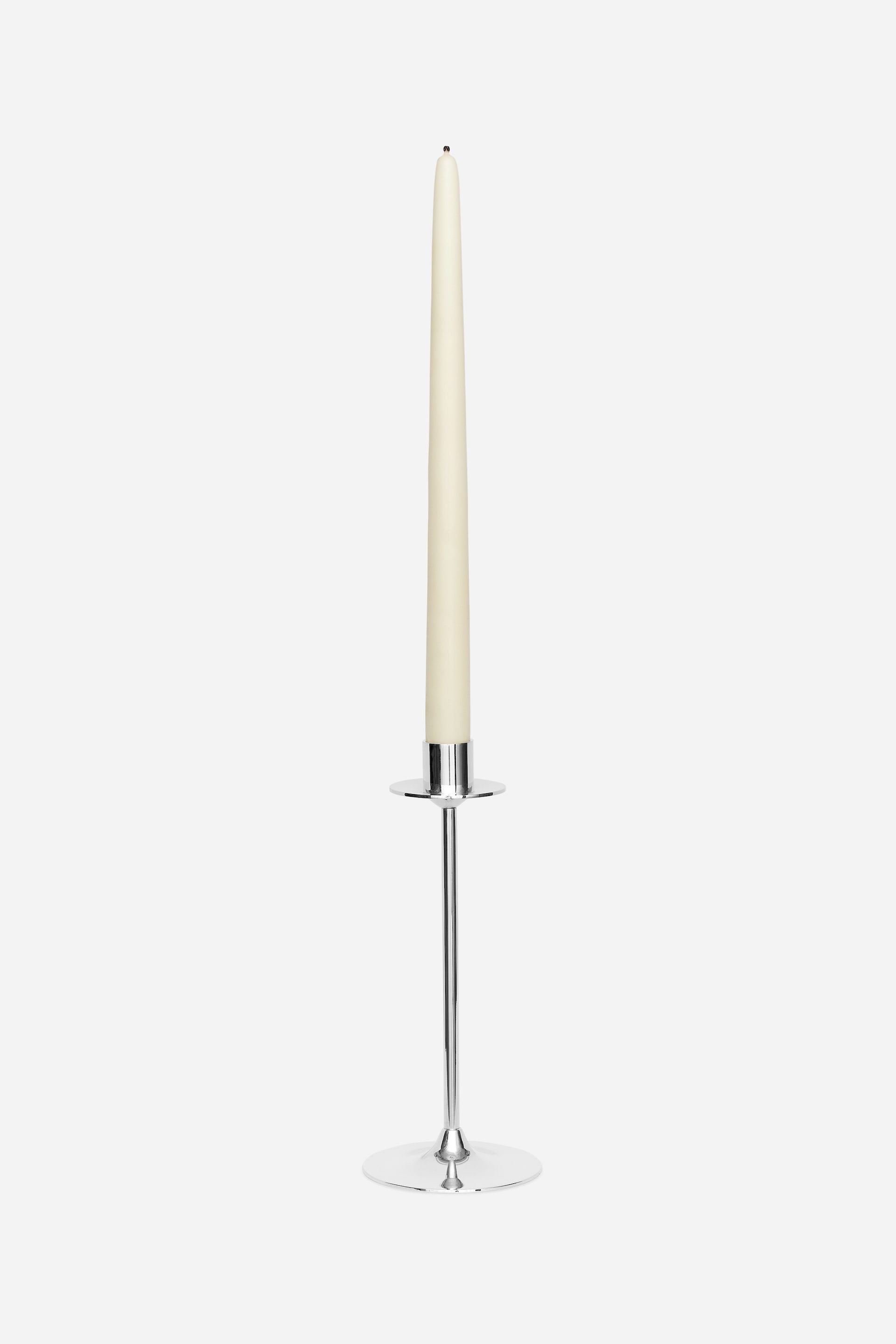 Visualizza l'immagine ingrandita: Una candela affusolata color avorio è posizionata in verticale in un candelabro di metallo argentato, con uno stoppino nero visibile sulla sommità. Il candelabro presenta uno stelo sottile, una base rotonda piatta e un piccolo portacandela rotondo in cima.