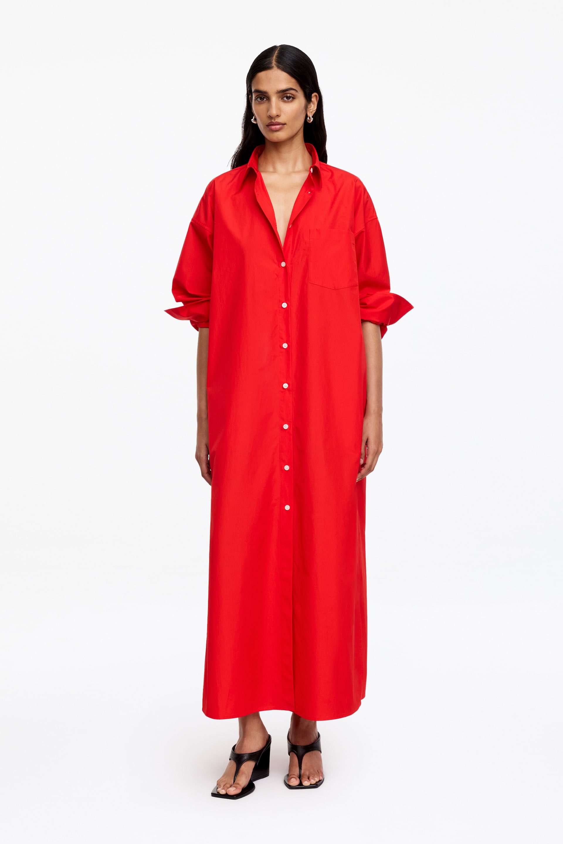 Agrandir l'image: Une robe-chemise rouge oversize présente un col pointu, une fermeture à boutons sur le devant avec des boutons blancs, et une poche plaquée unique sur la poitrine gauche. Ses manches longues sont retroussées aux coudes, et la robe pleine longueur s'étend jusqu'au milieu du mollet.