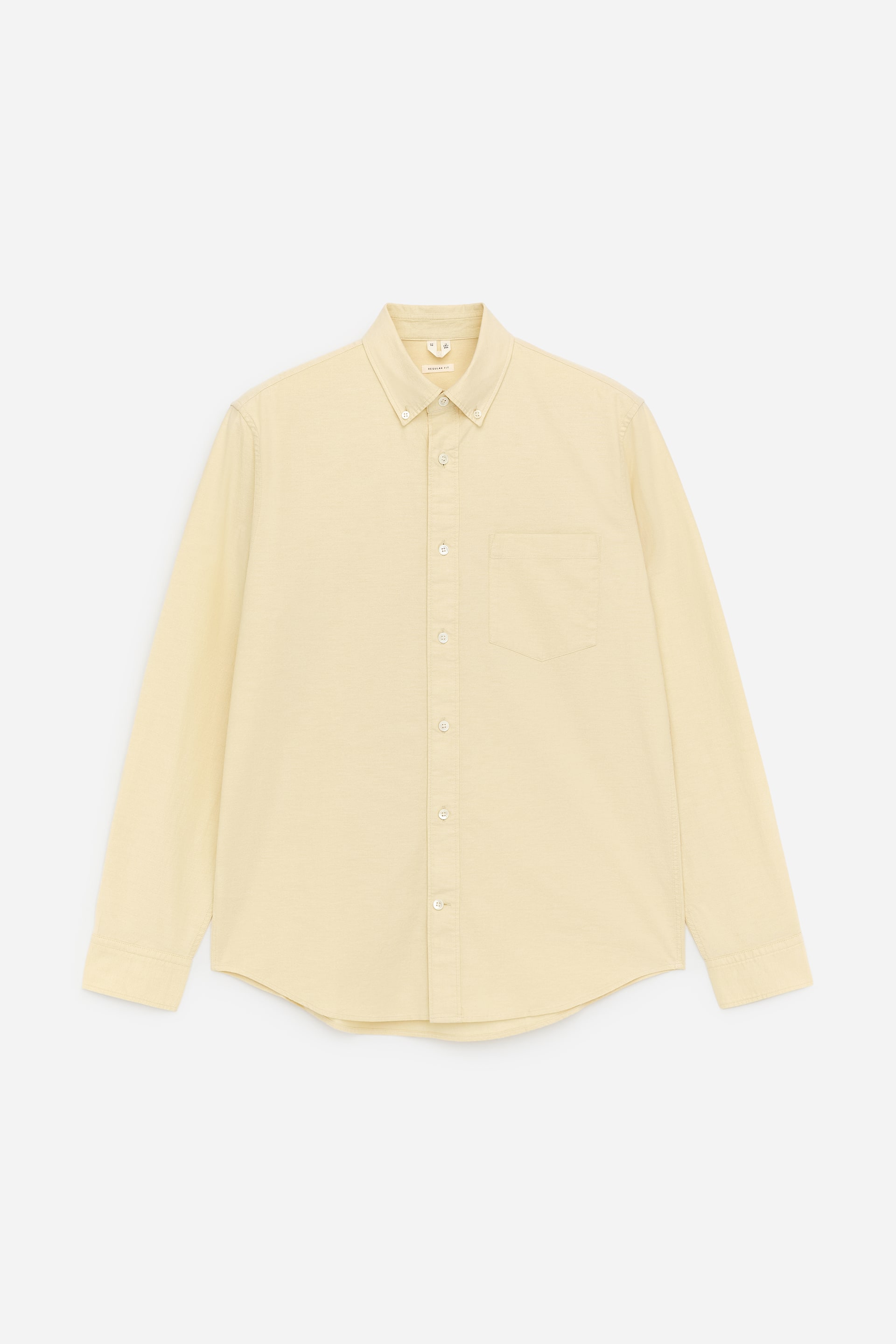 View larger image: Oxford Shirt. This light yellow Oxford shirt is shown from the front, featuring a button-down collar, a full button placket, a single patch pocket on the left chest, long sleeves with buttoned cuffs, and a curved hem.