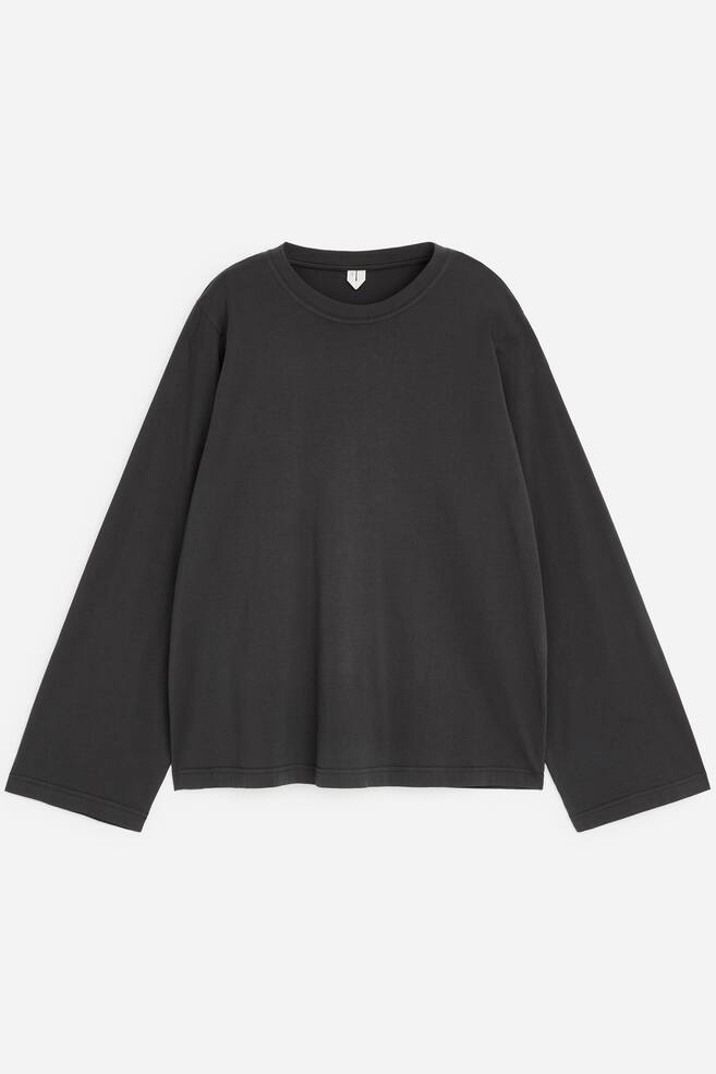 Een T-shirt met lange mouwen in vervaagd donkergrijs ligt plat en toont de voorkant en een ontspannen, losse pasvorm. Het kledingstuk heeft een geribde ronde hals, wijde lange mouwen met omgestikte boorden en een rechte zoom. - 1