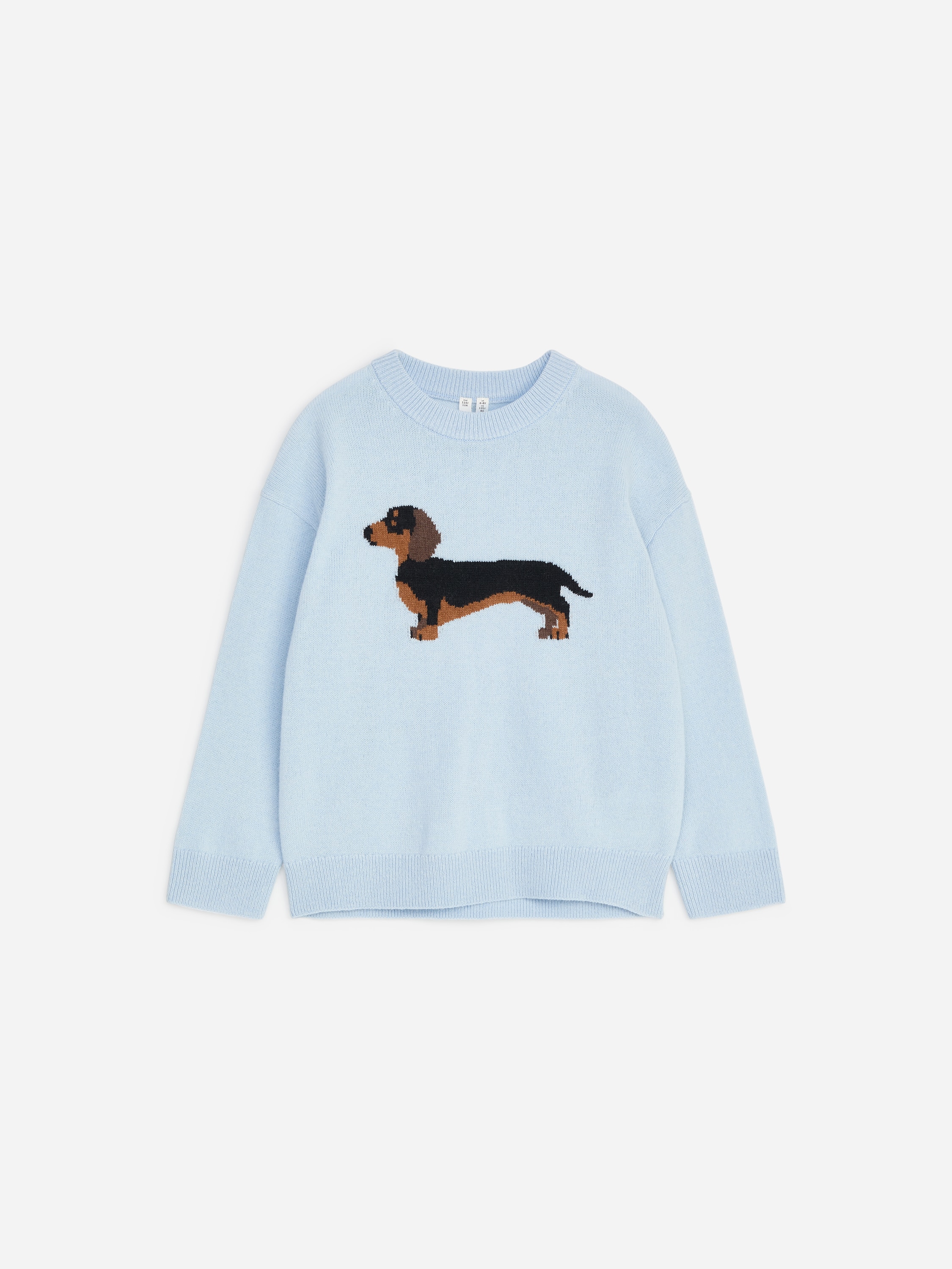 A light blue knitted jumper is shown from the front, featuring a ribbed crew neck and a prominent intarsia-knit dachshund motif across the chest. The close-up view highlights the fine knitted texture and the structure of the neckline.