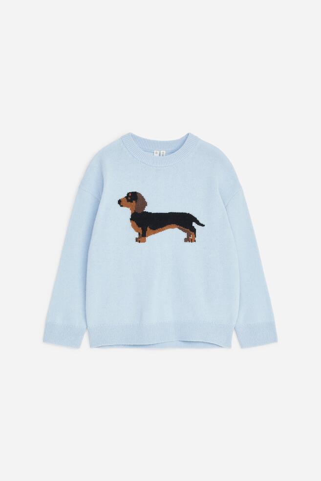 A light blue crew-neck knitted jumper is shown from the front, featuring a black and brown dachshund intarsia motif on the chest. The long-sleeved style features ribbed trims at the neckline, cuffs, and hemline. - 1
