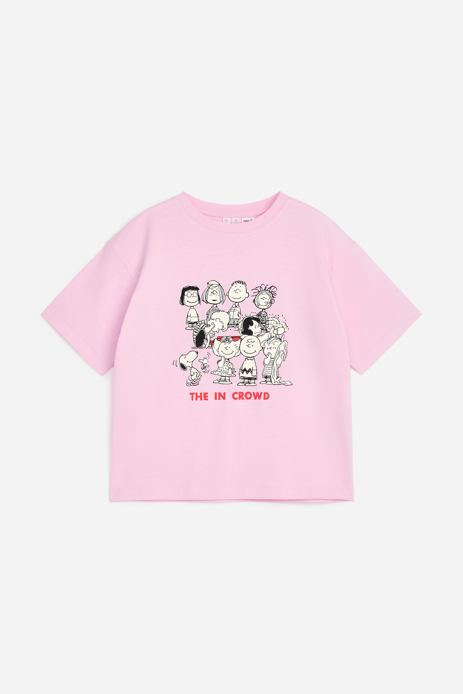 Vis større bilde: En rosa t-skjorte viser sin forside, med en svart-hvitt grafikk av flere Peanuts-figurer. Teksten "THE IN CROWD" vises i rødt under illustrasjonen, og den er designet med en ribbestrikket rund hals og korte ermer.