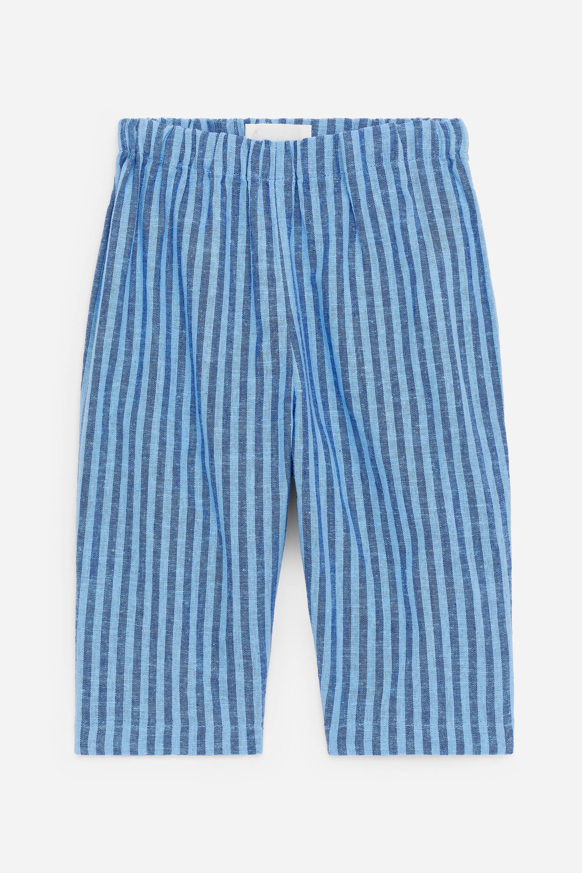 Προβολή μεγαλύτερης εικόνας: Παντελόνι με χαλαρή εφαρμογή, κατασκευασμένο από ένα απαλό μείγμα λινού και βαμβακιού, παρουσιάζει ένα μοτίβο με κάθετες ρίγες σε μπλε και ανοιχτό μπλε αποχρώσεις. Παρουσιάζεται από μπροστά, διαθέτοντας ελαστική και ρυθμιζόμενη ζώνη μέσης.