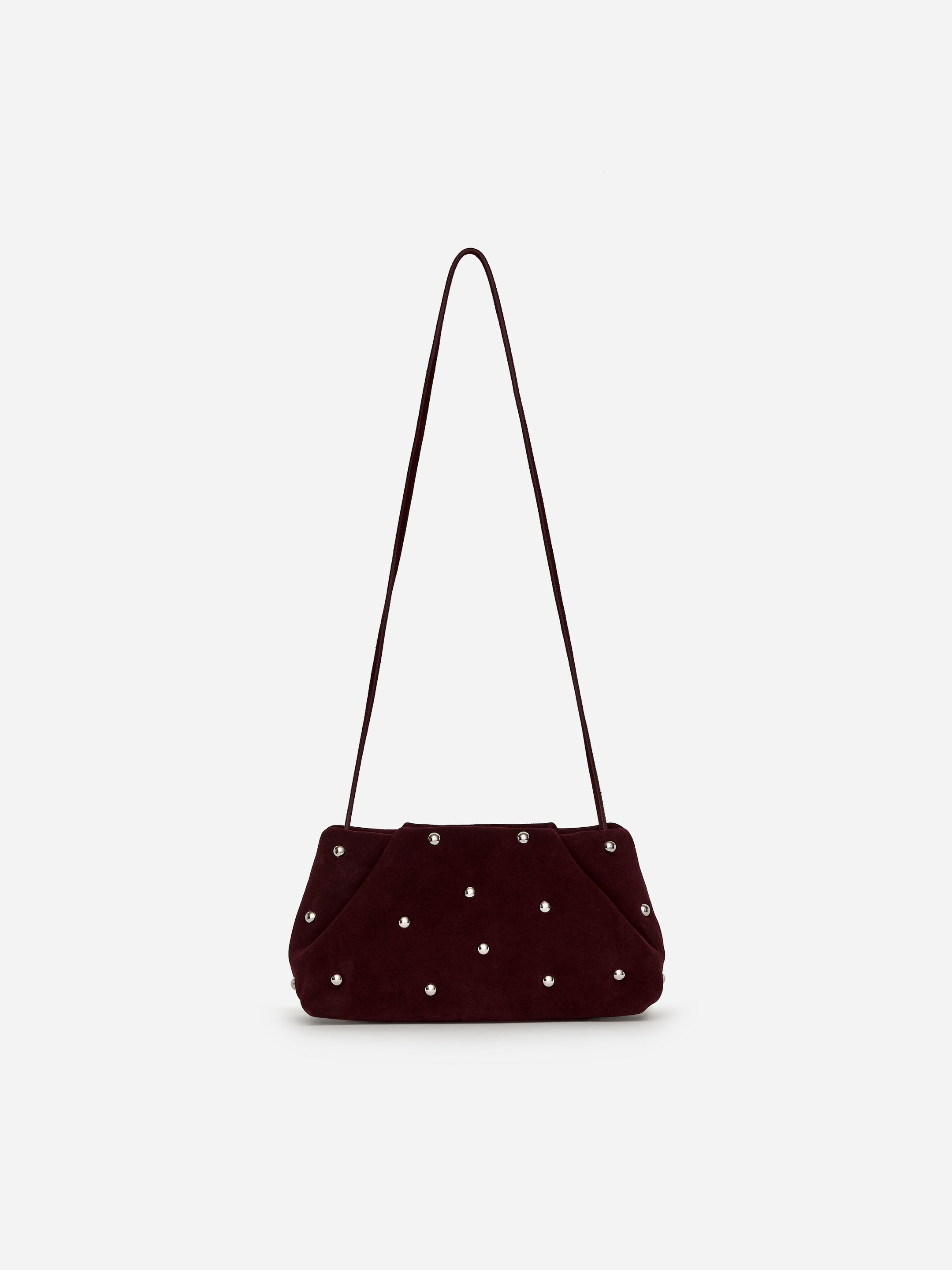 Größeres Bild ansehen: Eine bordeauxfarbene Wildleder-Clutch-Tasche zeigt sich von vorne und präsentiert eine weiche, strukturierte Form mit plissierten Seiten. Sie ist mit zahlreichen silberfarbenen Nieten auf der Vorderseite verziert, und ein dünner, passender Schulterriemen ist oberhalb der Tasche angebracht und sichtbar.