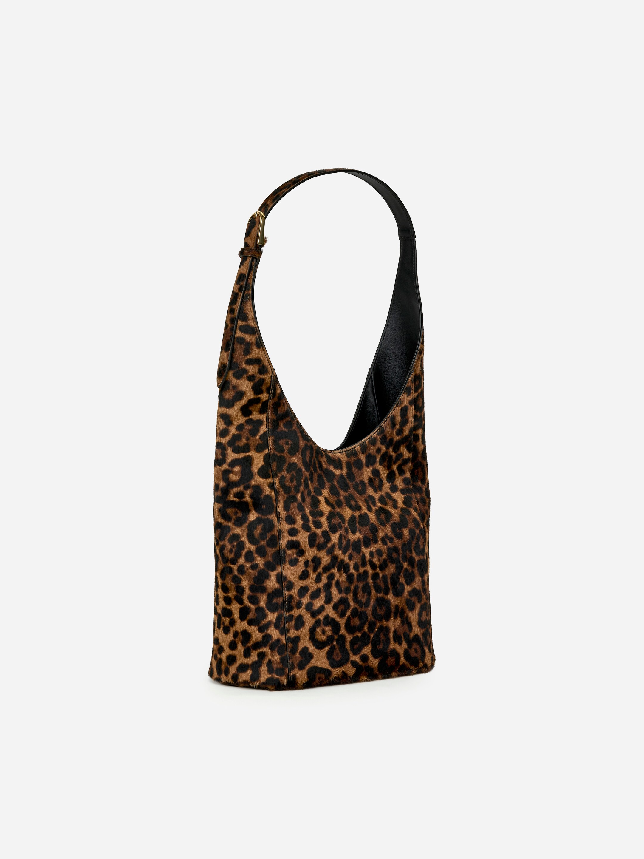 Grotere afbeelding bekijken: Een tote bag met een ponyhaar-effect in luipaardprint is schuin naar links gericht, met een verstelbare zwarte schouderriem met zichtbare gesp. Het interieur van de tas lijkt donker.