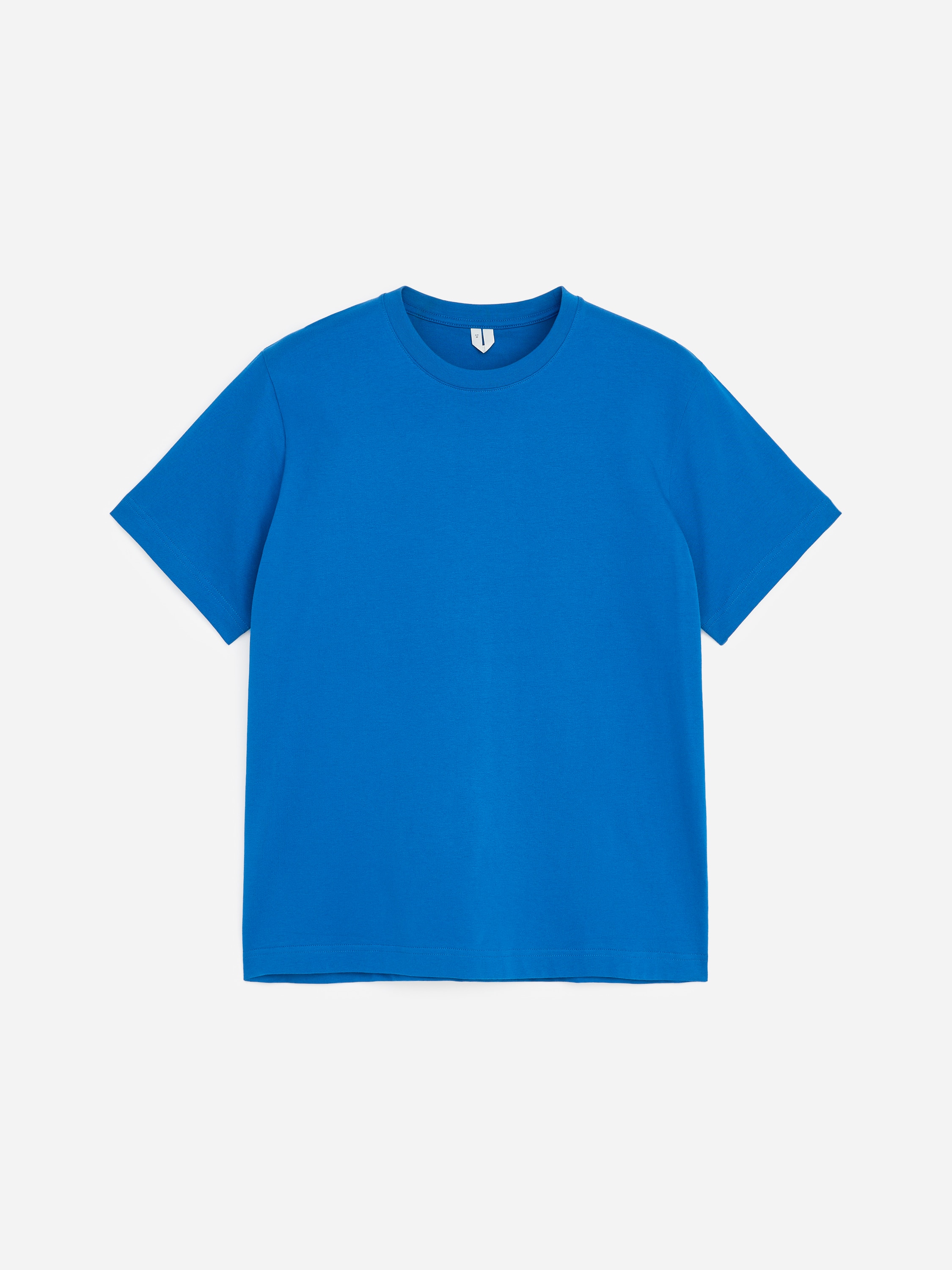 Un tricou cu guler rotund, albastru aprins Èi cu mÃ¢necÄ scurtÄ, este purtat de model. Tricoul are o croialÄ clasicÄ, fluidÄ, Èi este asortat cu pantaloni gri Ã®nchis.