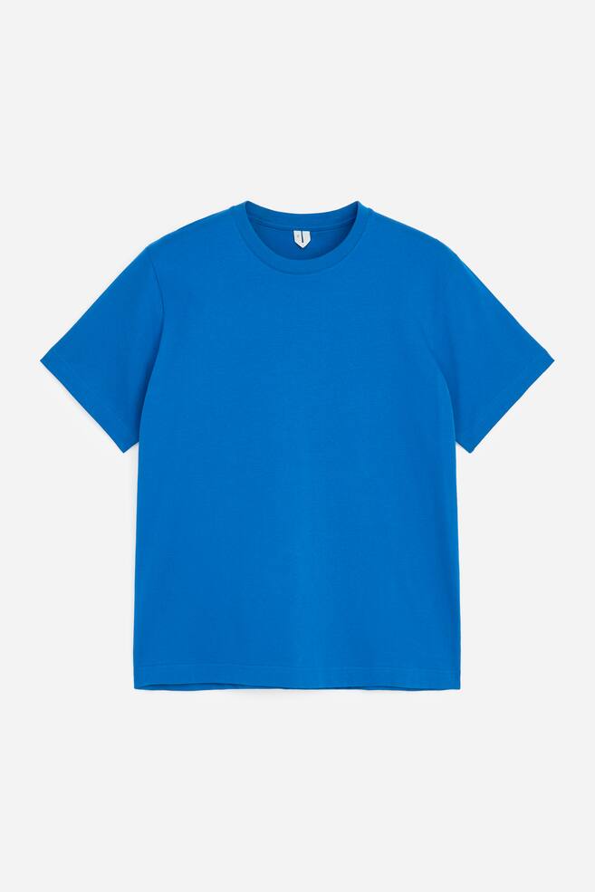 En klarr blÃ¥ t-shirt Ã¤r fotograferad framifrÃ¥n och har rund hals med ribbad kant, korta Ã¤rmar och rak nederkant. - 1