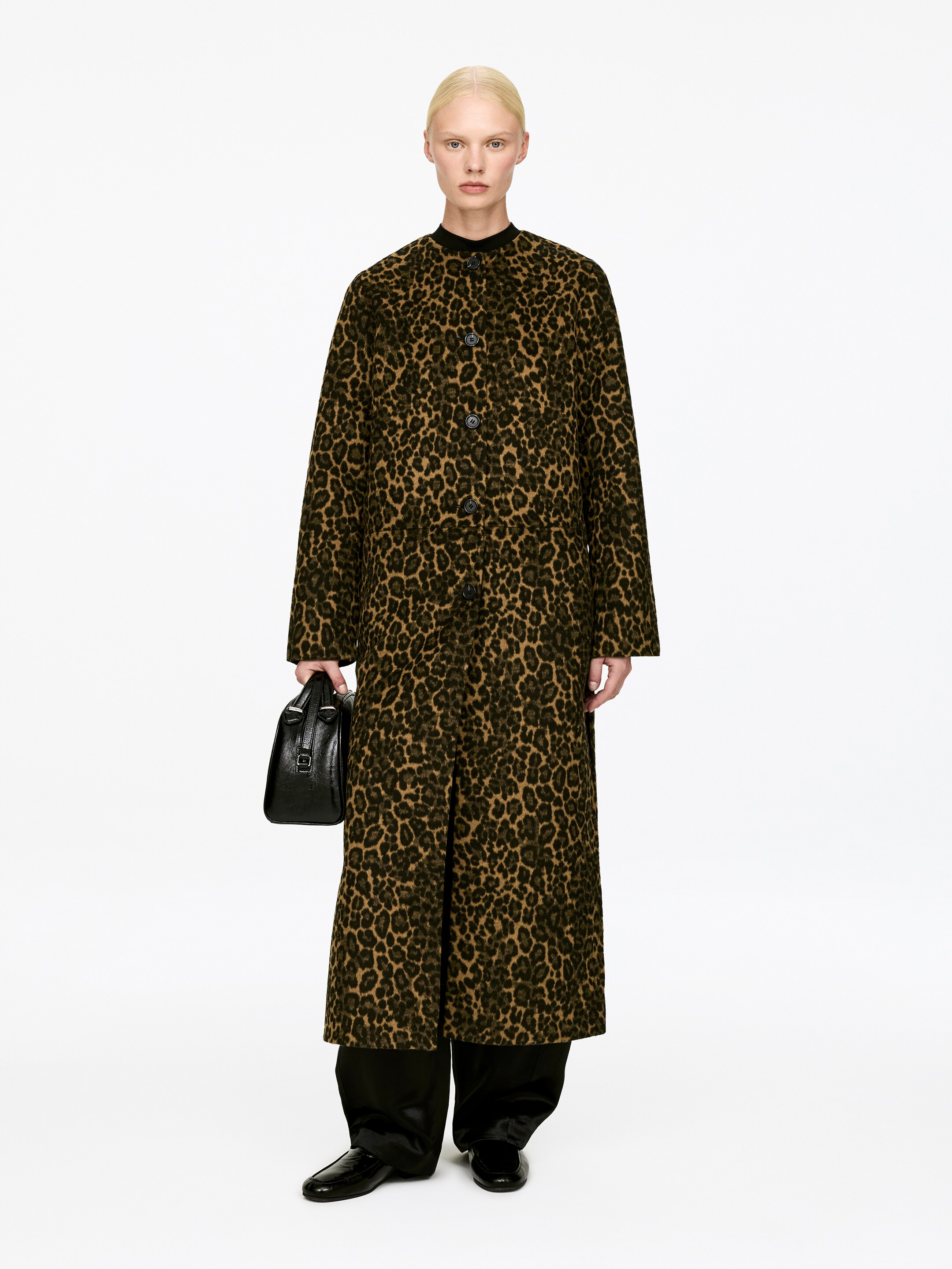 Vis større bilde: En fotsid kåpe viser et leopardmønster i brun, svart og beige fra en frontvisning, med en rett, avslappet passform, en ståkrage og en frontlukking med synlige svarte knapper.