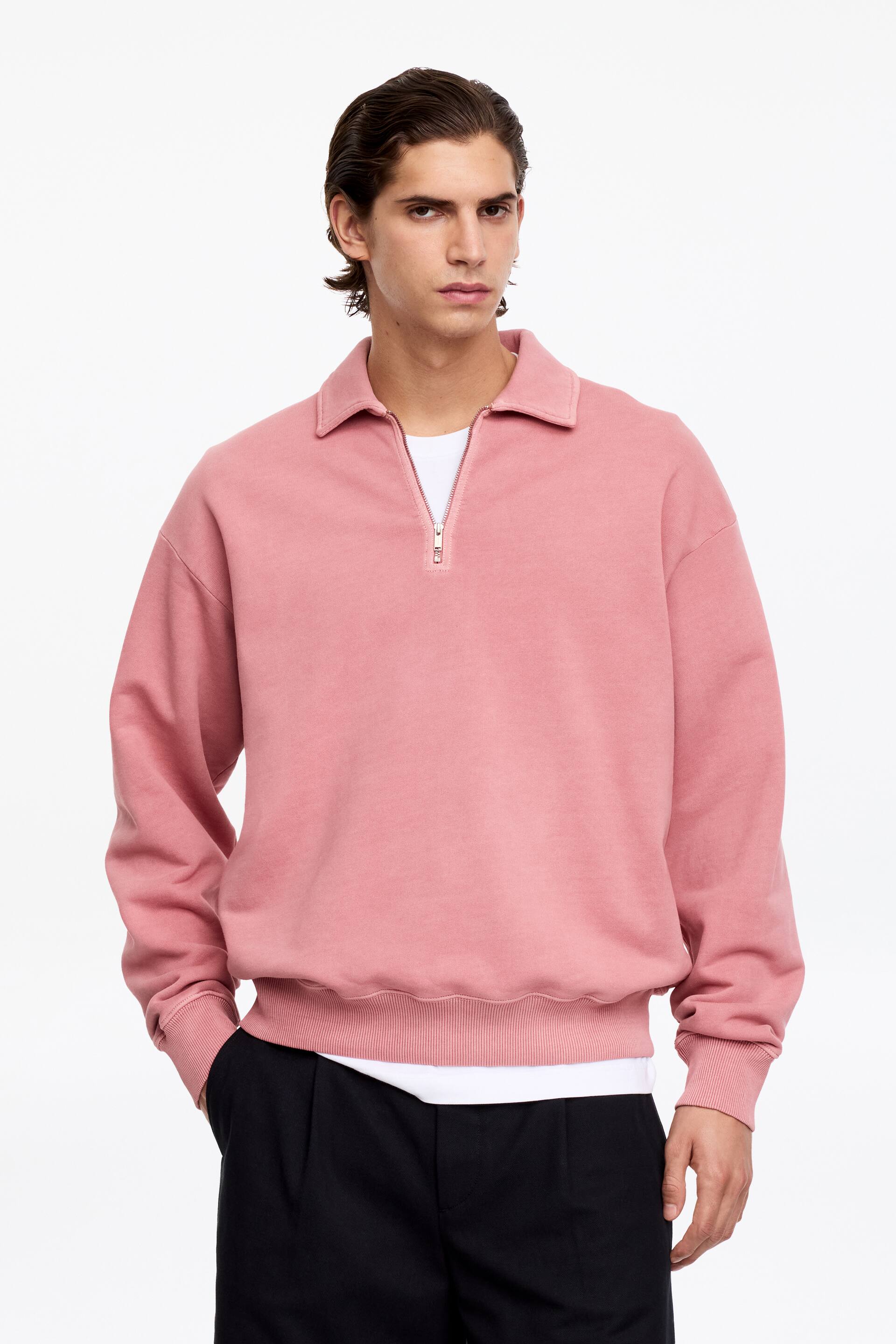 Visa större bild: En rosa kvartdragkedja tröja presenteras framåt, med en spetsig krage, en kvartdragkedja, långa ärmar med ribbade muddar och en ribbad fåll. En vit t-shirt är lagrad under, synlig vid halsringningen och fållen.