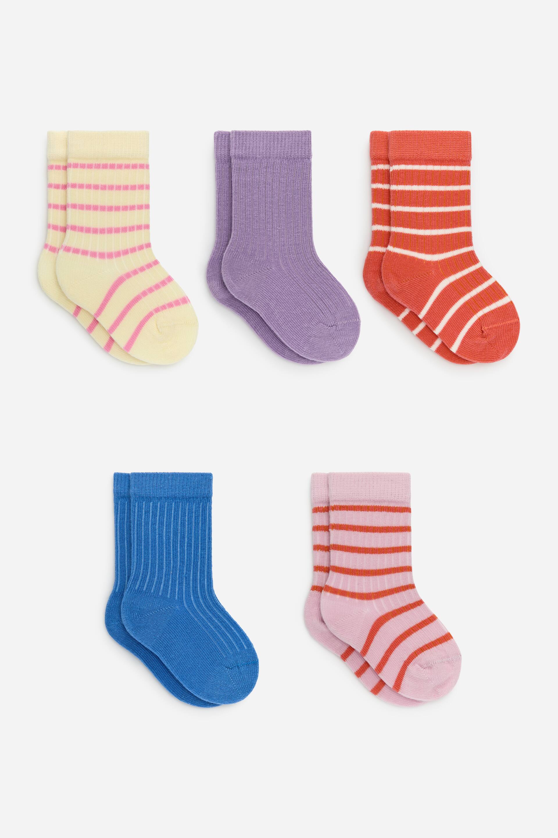 Ver imagen más grande: Un conjunto de cinco pares de calcetines de punto acanalado se presenta extendido. Los calcetines incluyen un par amarillo pálido con rayas horizontales discontinuas en rosa, un par sólido de color lavanda, un par naranja-rojo con rayas horizontales blancas, un par sólido azul y un par rosa claro con rayas horizontales naranja-rojo.