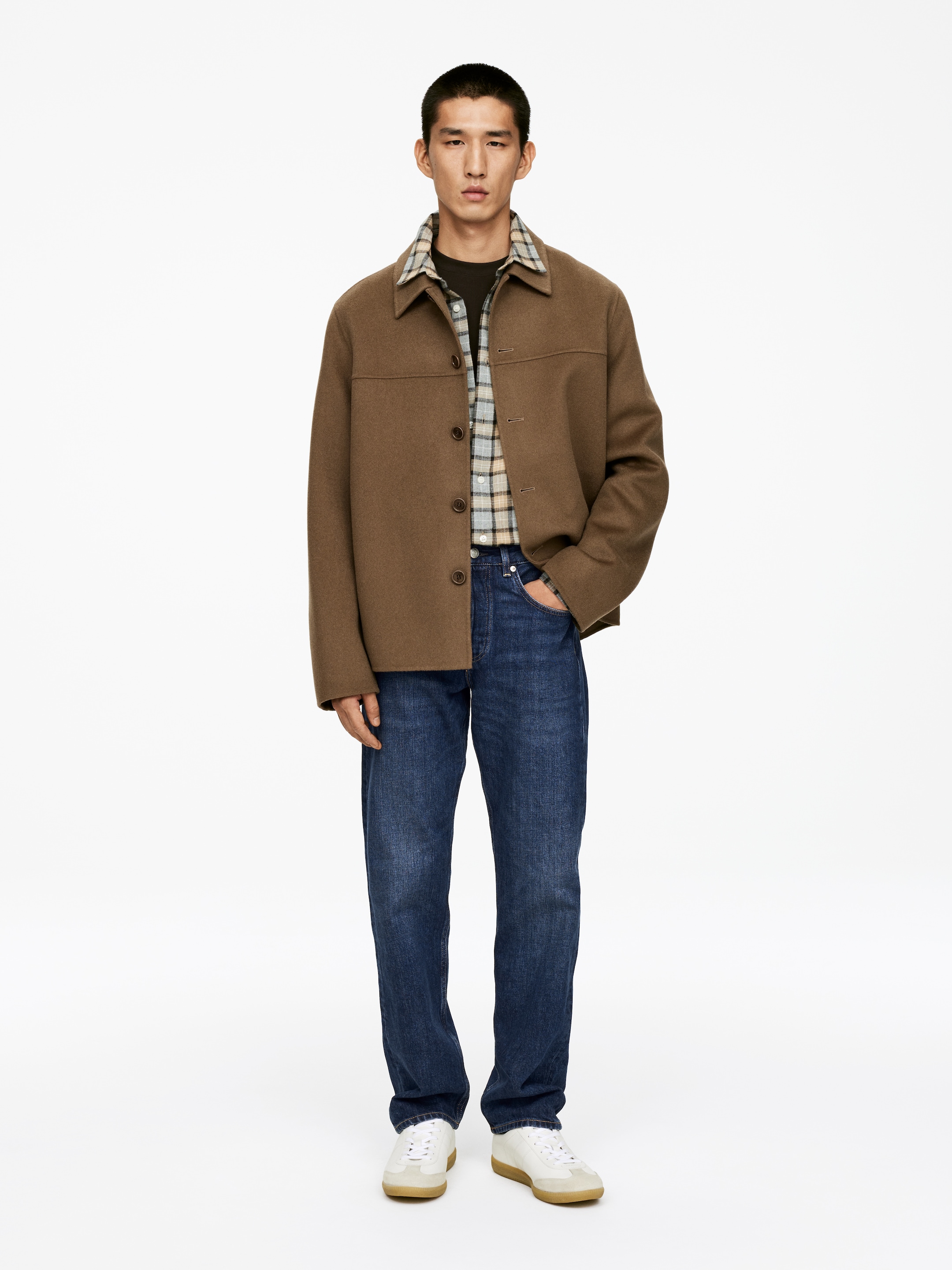 Visa större bild: OCEAN-jeans, skurna av mörkblå denim utan stretch med en lös, bekväm passform, medelhög midja och raka, fullängdsben, bärs av modellen. Jeansen är stylade med en brun jacka och en rutig skjorta.