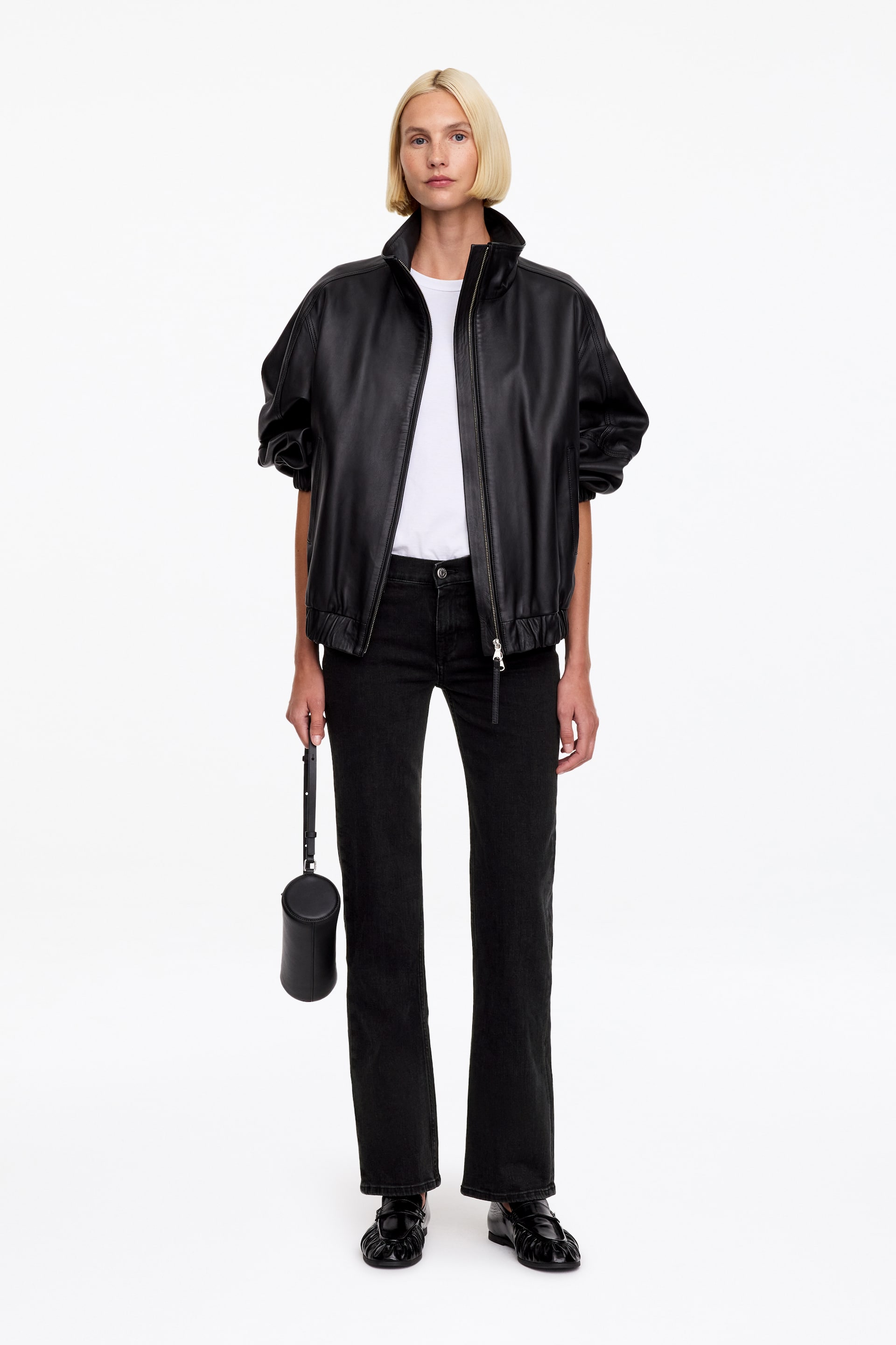Ver imagen más grande: La modelo lleva unos vaqueros negros de pierna recta con corte slim. Los vaqueros se combinan con una camiseta blanca por dentro, una chaqueta de cuero negra abierta y unos mocasines negros.