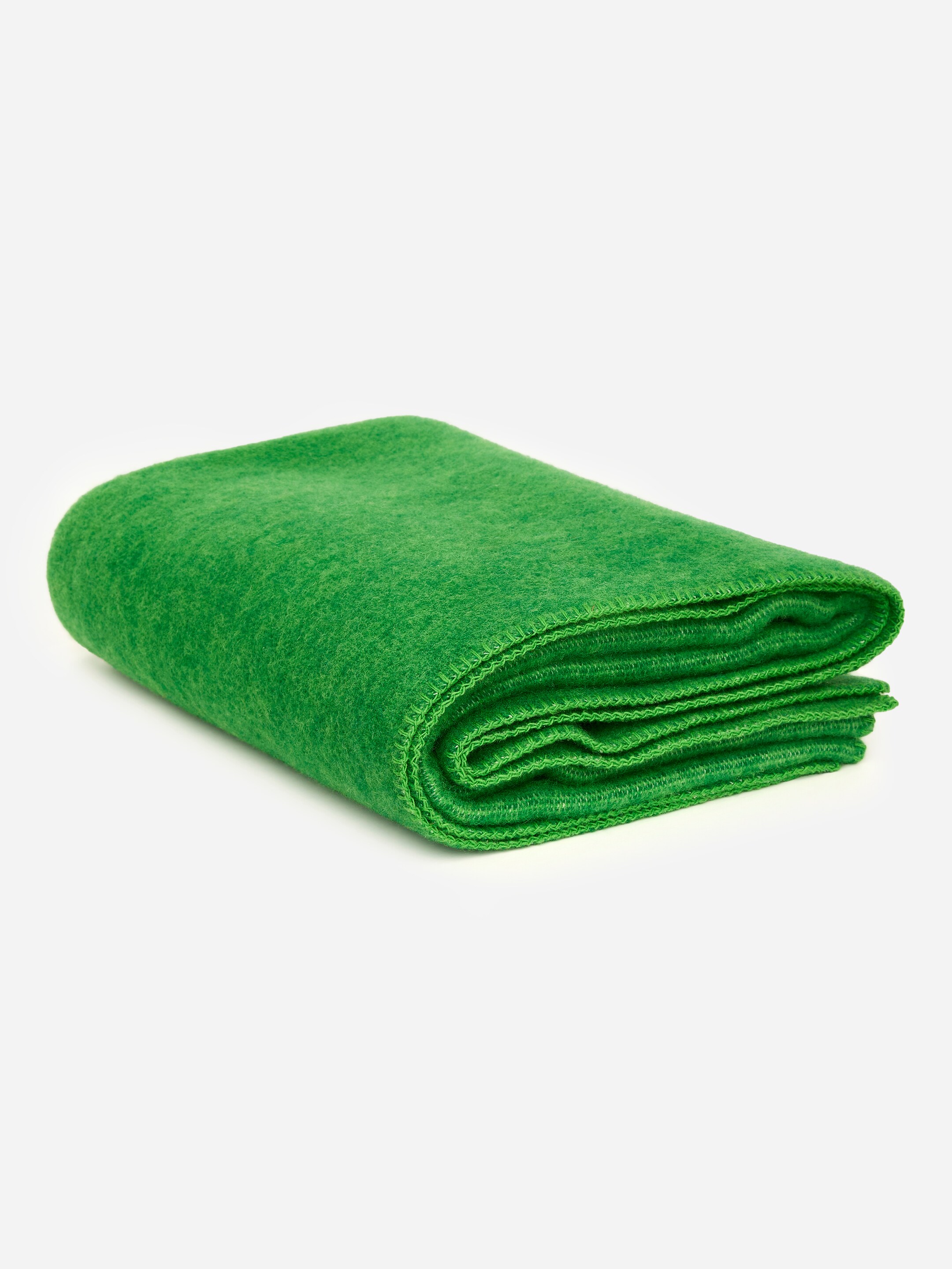 Grotere afbeelding bekijken: Een stevige wollen deken is netjes opgevouwen en vertoont een levendige groene kleur en een zachte, egale textuur. Dekkenstiksels zijn zichtbaar langs de gevouwen randen.