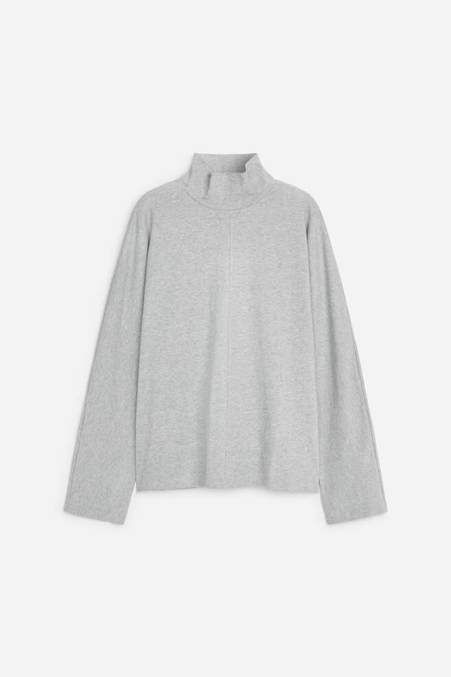 A light grey mÃ©lange long-sleeve top is shown from the front, featuring a high mock neck and a distinct vertical seam running down the centre front. The top is shown in a relaxed fit with wide, straight-cut sleeves and a clean, straight hem. - 1
