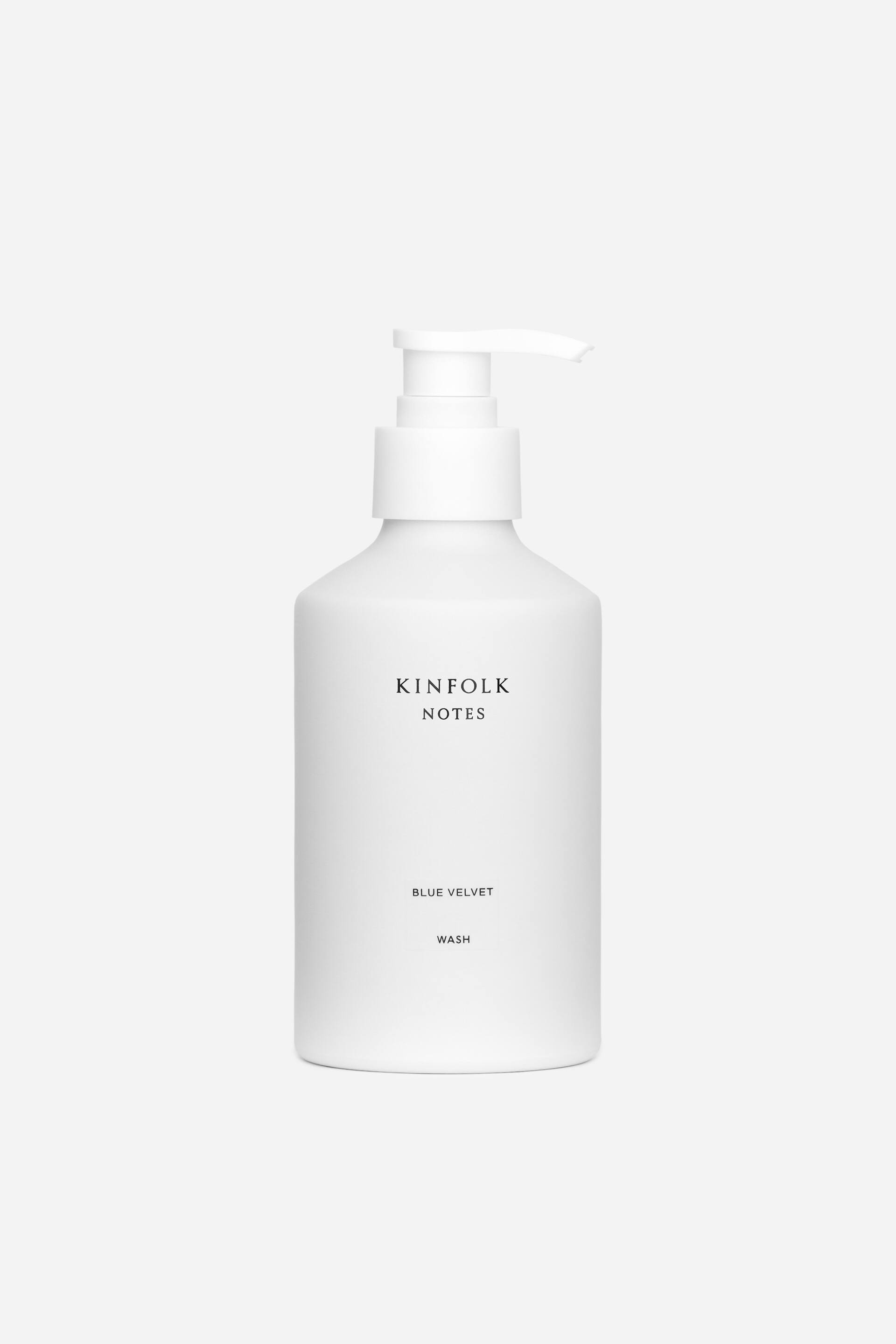 Grotere afbeelding bekijken: Een witte, matte fles met een pompdispenser toont zijn voorkant, met de woorden "KINFOLK NOTES BLUE VELVET WASH" gedrukt in zwart.