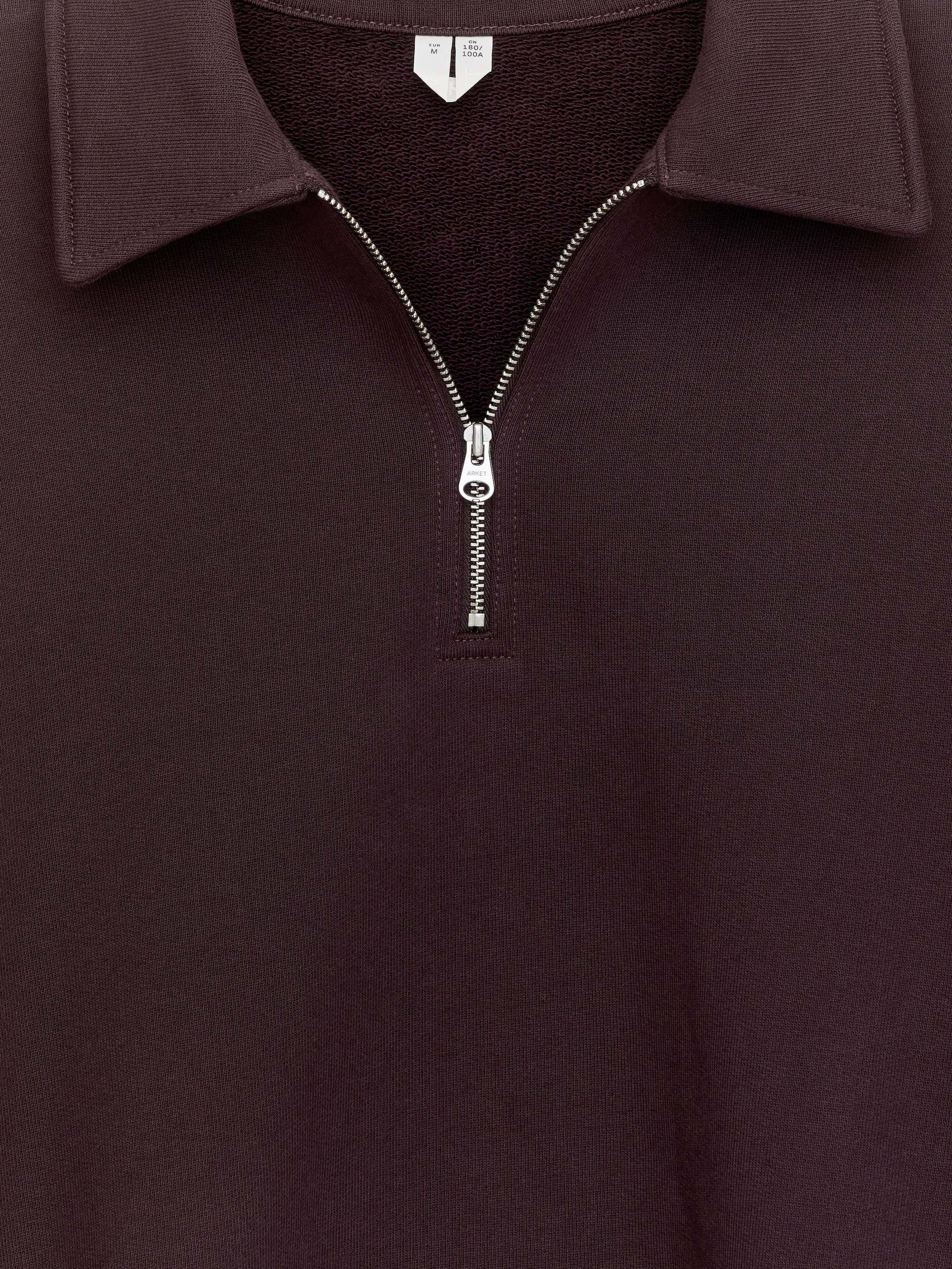 Agrandir l'image: Un sweat-shirt en coton bordeaux foncé est présenté de face, avec un col classique à pointes et une fermeture éclair métallique argentée à mi-hauteur.