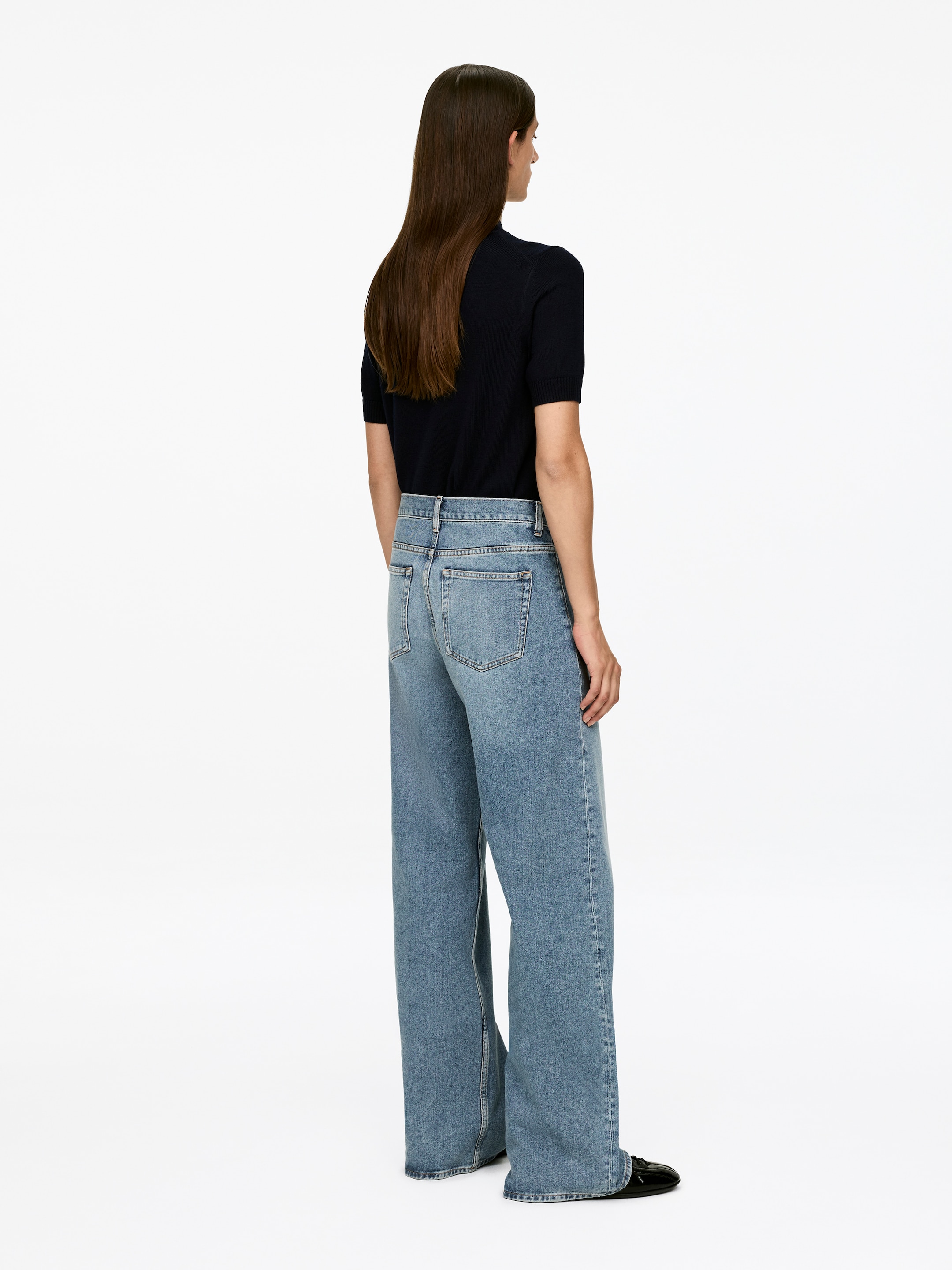 Visualizza immagine più grande: I jeans LUPINE vengono indossati dalla modella, che è di spalle rispetto all'osservatore. I jeans in denim azzurro chiaro sono caratterizzati da una vita alta, una vestibilità aderente sui fianchi e gambe svasate, con tasche applicate visibili sul retro.