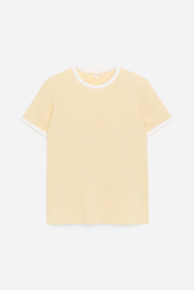 Een A FRONT slim-fit T-shirt in lichtgeel is voorzien van een zachte katoenen ribconstructie. Het is uitgevoerd met capmouwen en een witte contrasterende bies bij de ronde hals en de mouwboorden. - 1