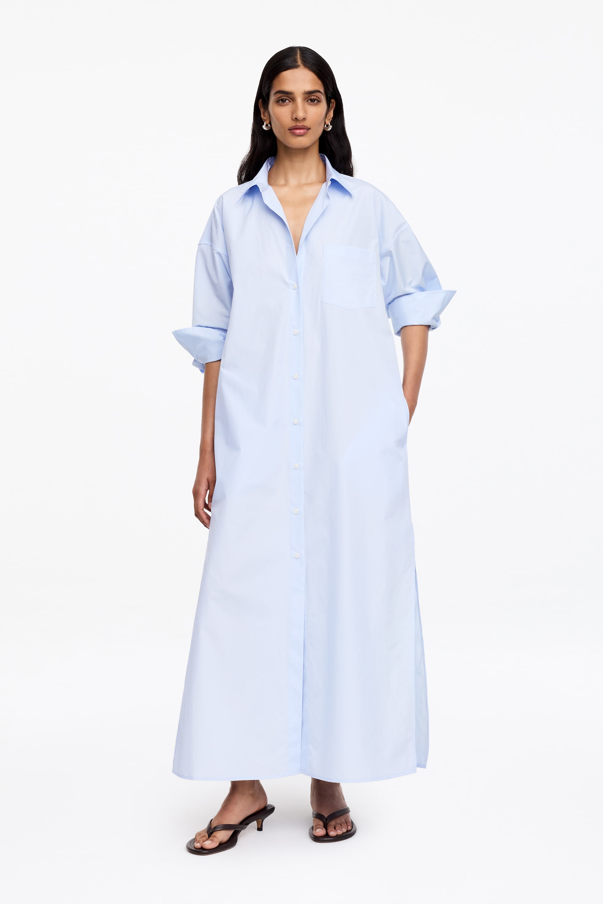 Agrandir l'image: Une robe chemise maxi bleu clair est orientée vers l'avant, avec un col pointu, une patte de boutonnage pleine longueur avec des boutons blancs, et une seule poche plaquée sur la poitrine. Ses manches longues sont retroussées jusqu'aux coudes, et la robe à coupe décontractée s'étend jusqu'au sol.