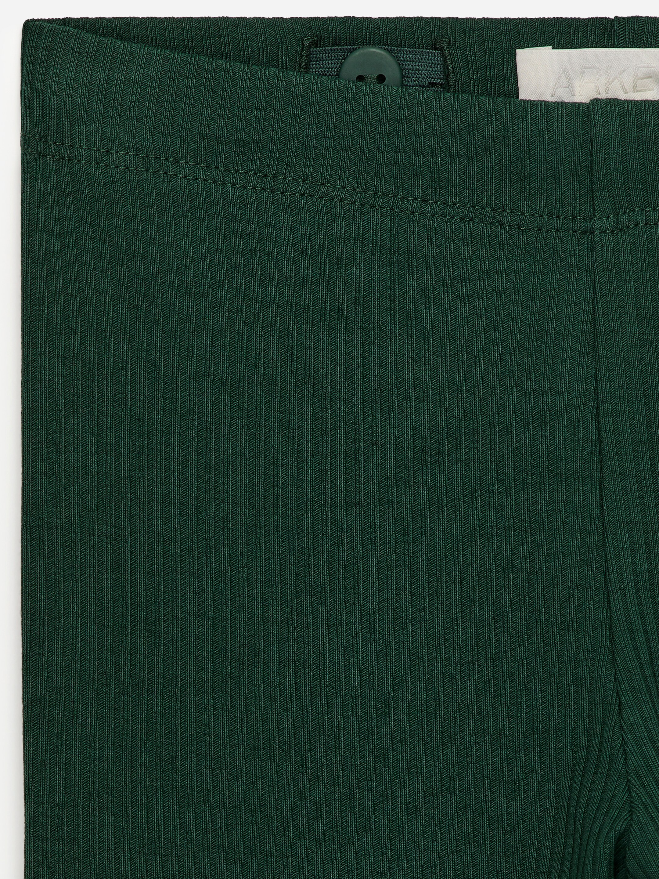 Grotere afbeelding bekijken: Donkergroene leggings worden van voren getoond, gemaakt van een ribgebreide jersey stof met zichtbare verticale ribbels. De tailleband heeft een verstelbare elastiek met een donkere knoop die aan de binnenkant zichtbaar is.