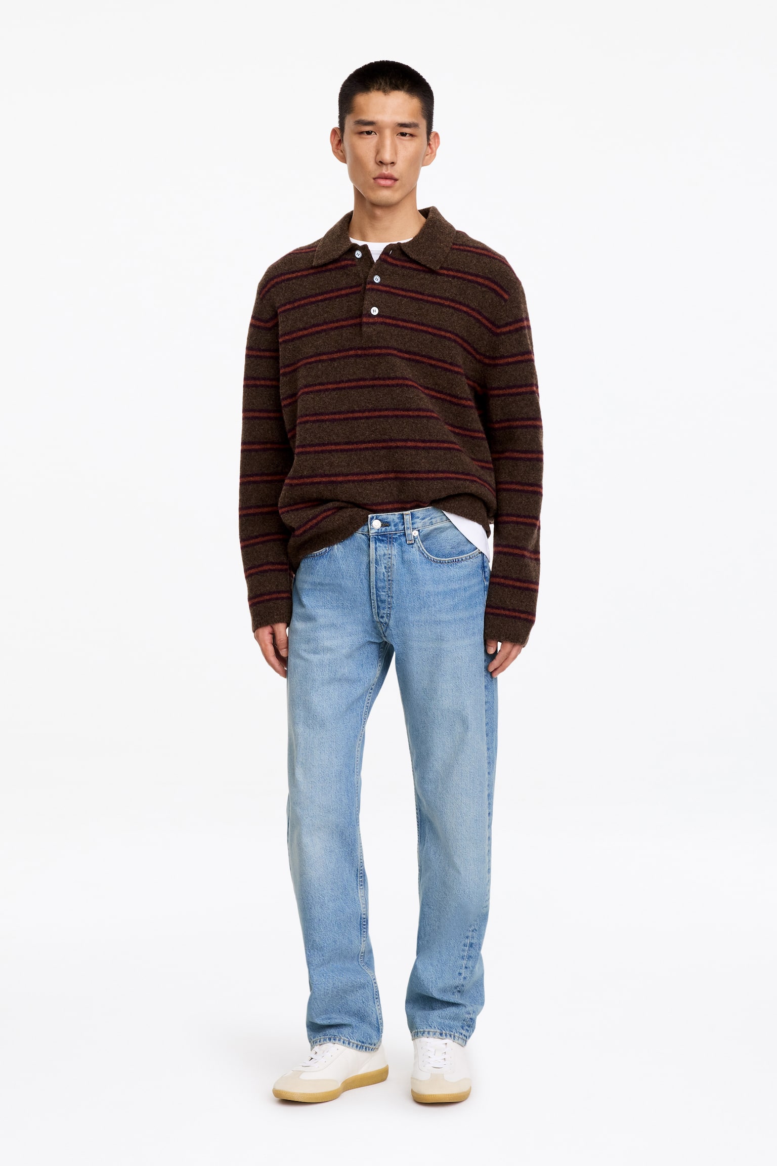 Lyseblå, rette denimjeans med middels høy midje og regular fit bæres av modellen. Jeansene er stylet med en brun stripete poloskjorte delvis stukket ned i livet og hvite sneakers. - 1