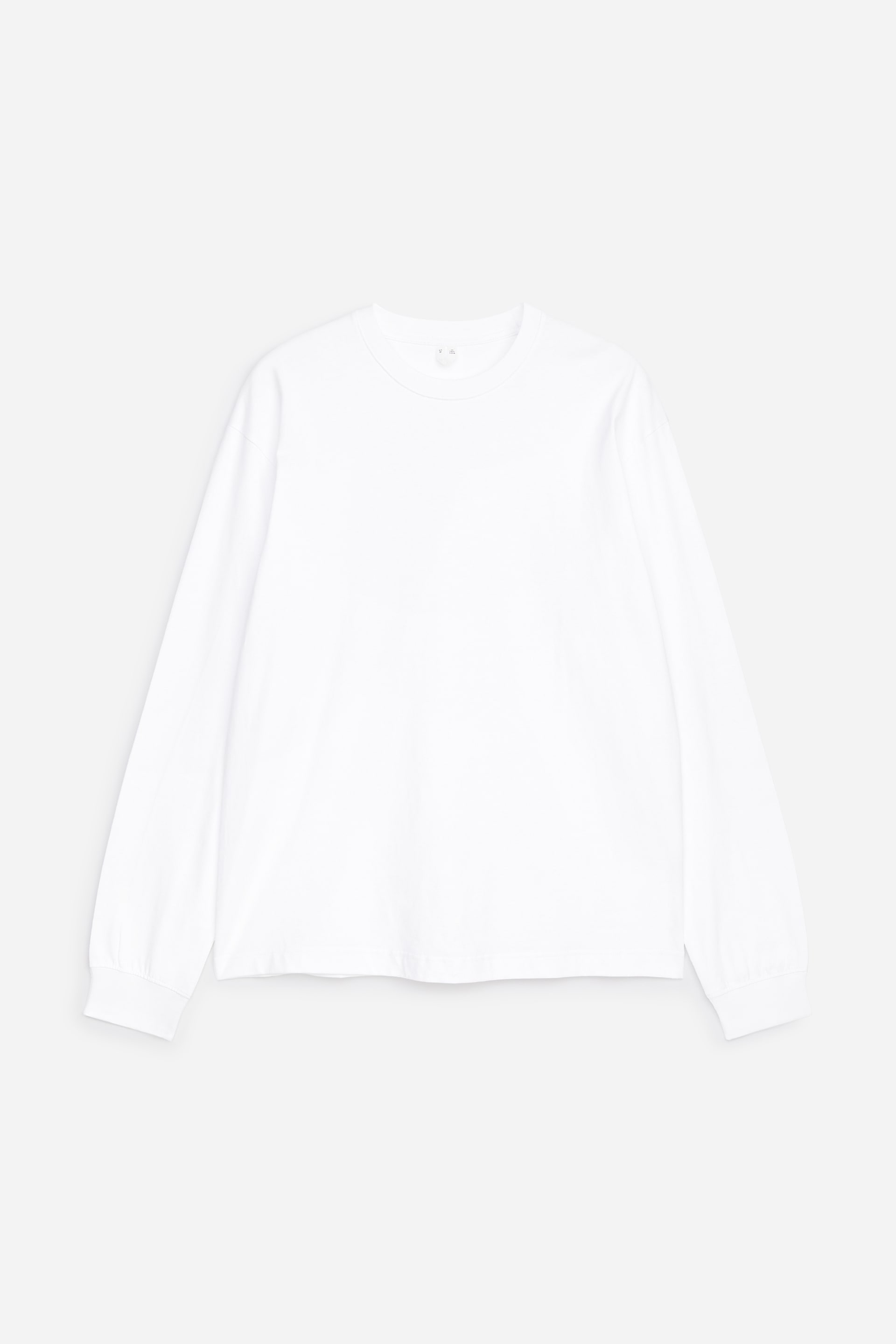 Zobacz większy obraz: Biały bawełniany T-shirt z długim rękawem, prezentowany od przodu i rozłożony na płasko, charakteryzuje się luźnym krojem, opuszczonymi ramionami, prążkowanym dekoltem typu crew neck oraz prążkowanymi mankietami.
