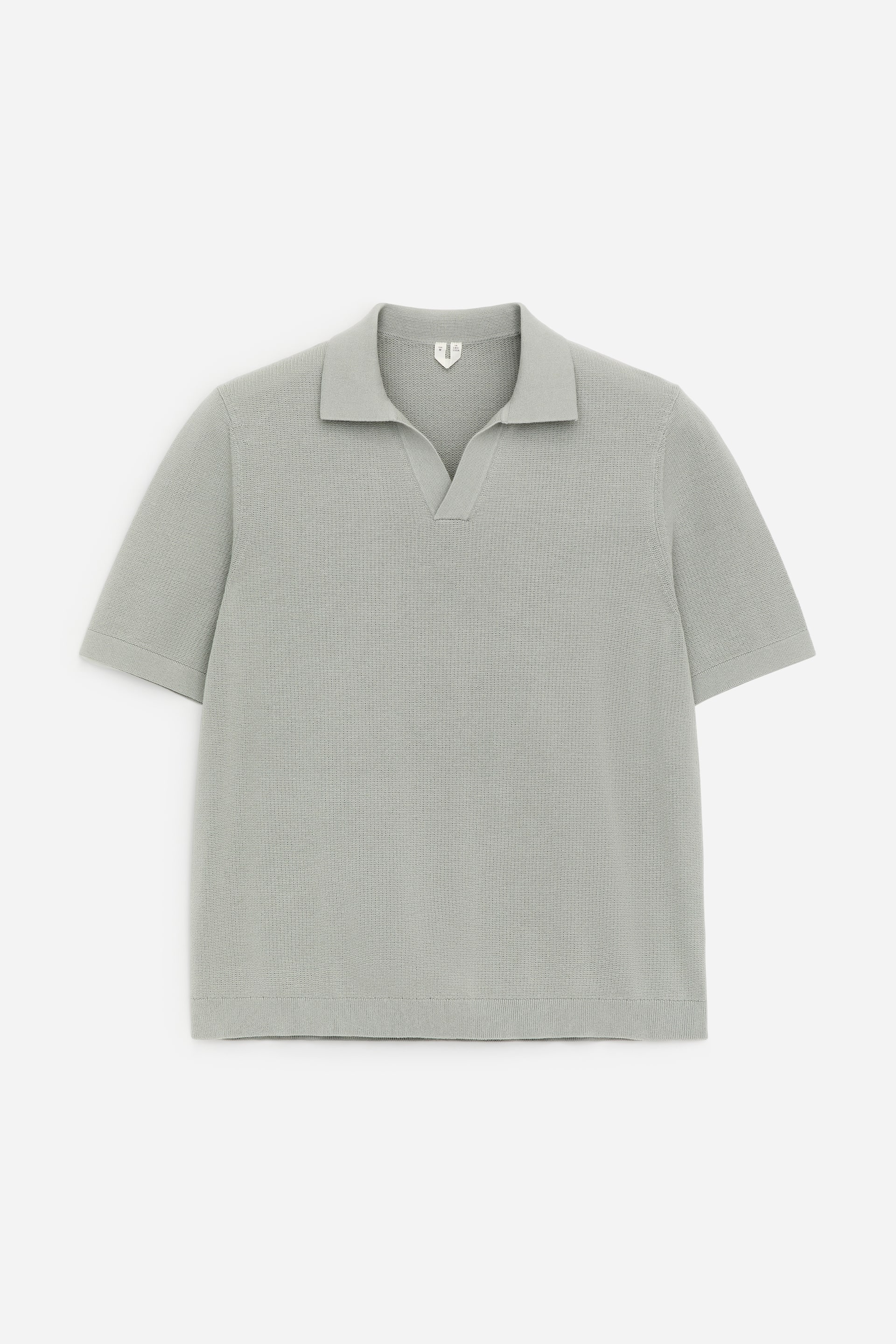 Visualizza immagine più grande: Una polo lavorata a maglia di colore verde salvia chiaro viene presentata FRONTE, caratterizzata da una superficie testurizzata, maniche corte, vestibilità regolare e uno scollo a V che forma un colletto aperto.