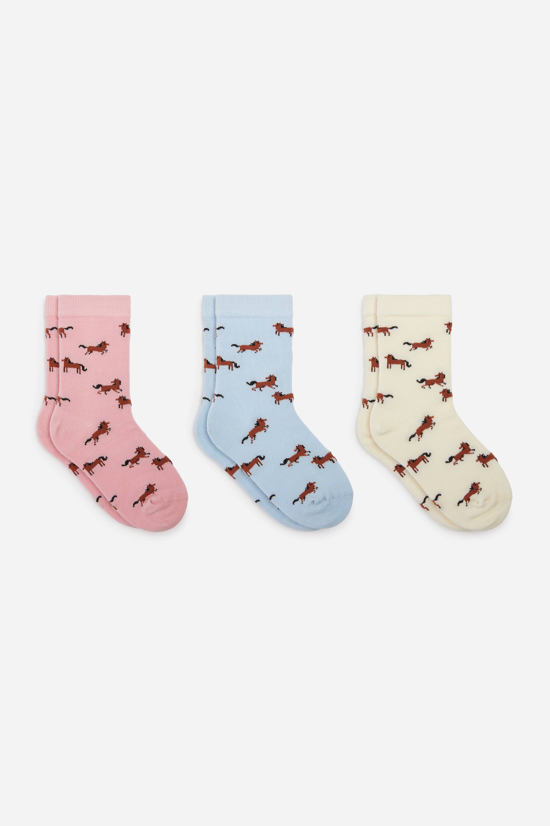 View larger image: A set of three pairs of socks in pink, light blue, and cream is laid flat, showcasing an all-over pattern of small brown horses. Each sock features a ribbed cuff and is facing right in profile to display the heel and toe construction.