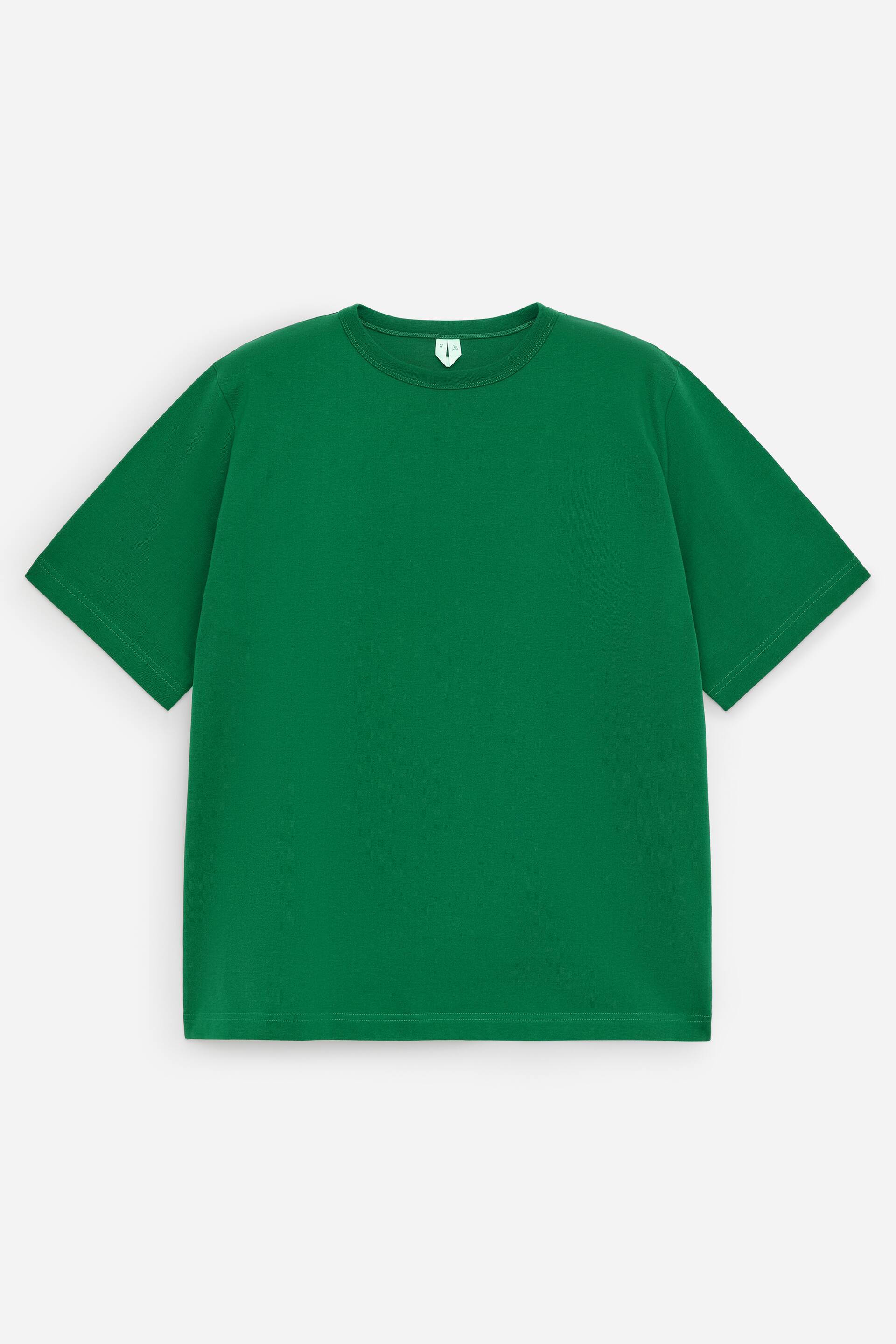 Visa större bild: En grön t-shirt är vänd framåt, med en klassisk crewneck och 1x1-ribb, och visar en lätt oversized-siluett med längre ärmar och en generös skärning över kroppen. En vit etikett med en grön symbol syns i nacken.