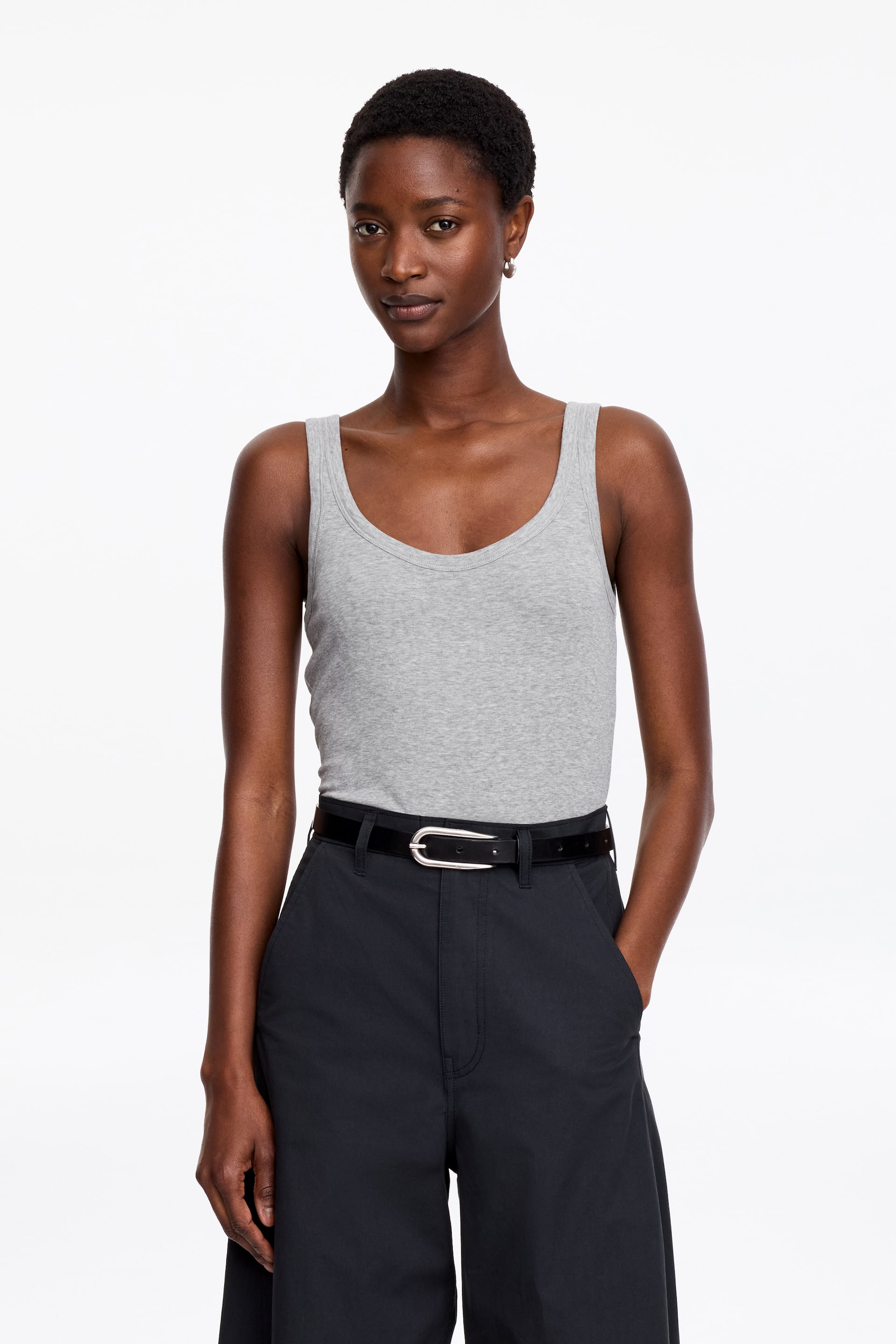 Agrandir l'image: Un débardeur gris, avec une encolure dégagée, une silhouette sans manches et une coupe classique, est porté par le mannequin. Le mannequin l'associe à un pantalon foncé et une ceinture noire.