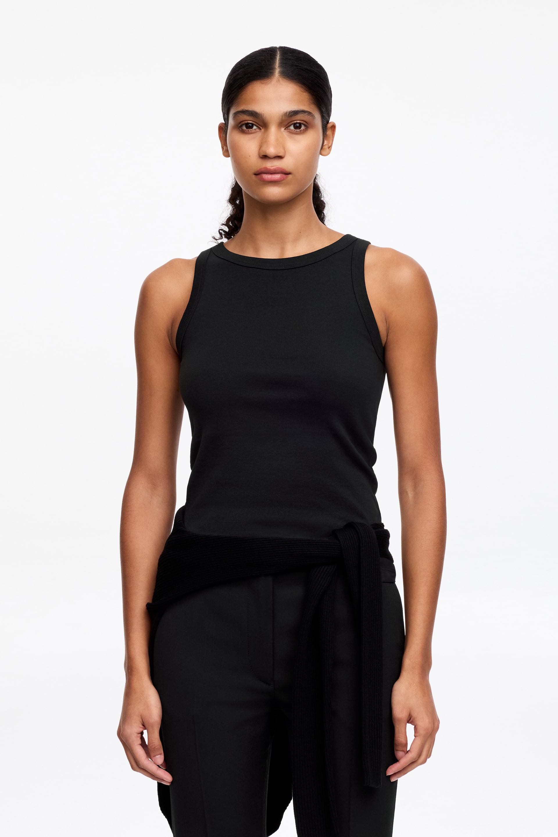 Größeres Bild anzeigen: Ein schwarzes Tanktop mit einer figurbetonten Silhouette, einem gerippten Rundhalsausschnitt und einem ärmellosen Design.