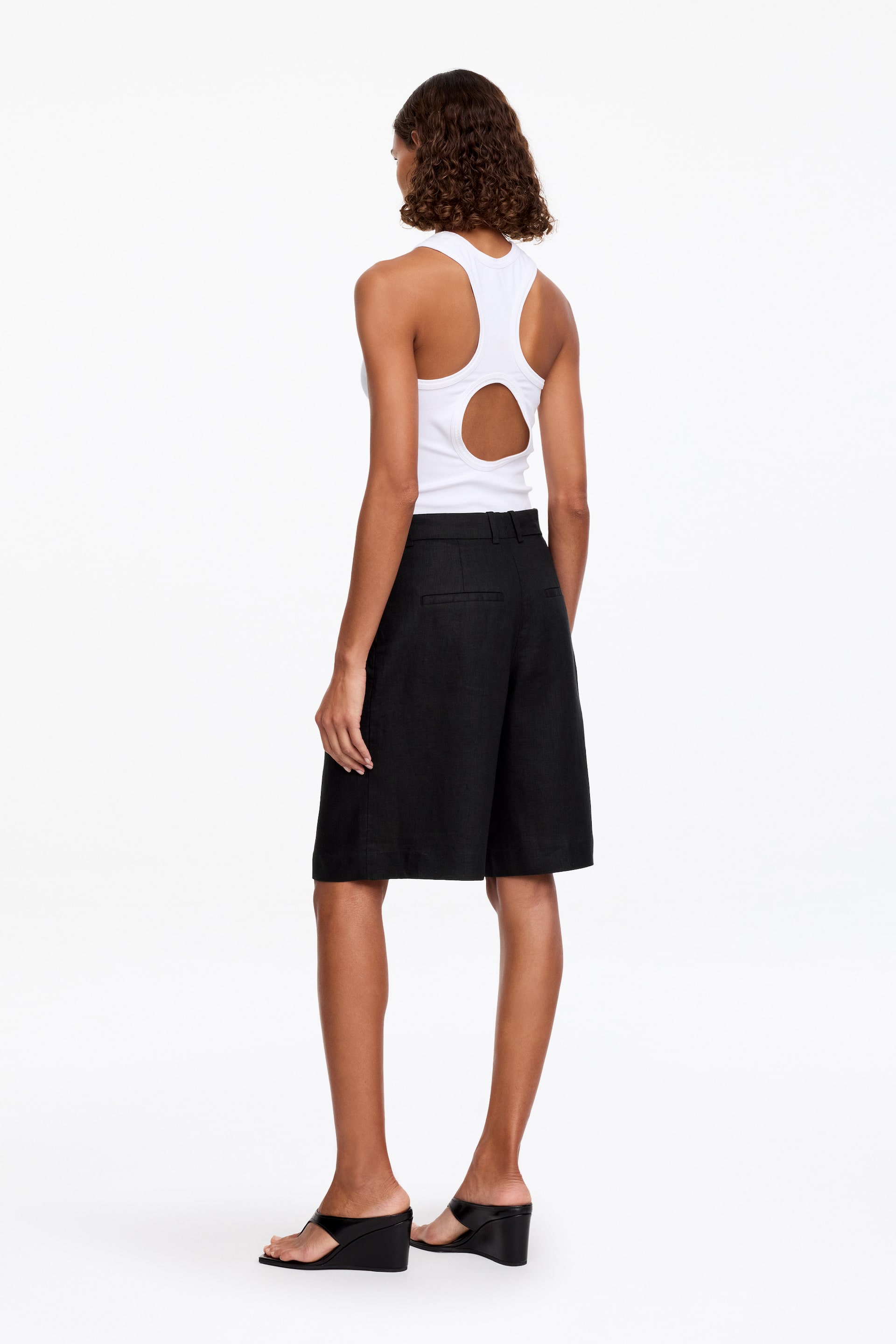 View larger image: A white ribbed vest is displayed from the back. It features a racerback design and a large circular cutout on the upper back.