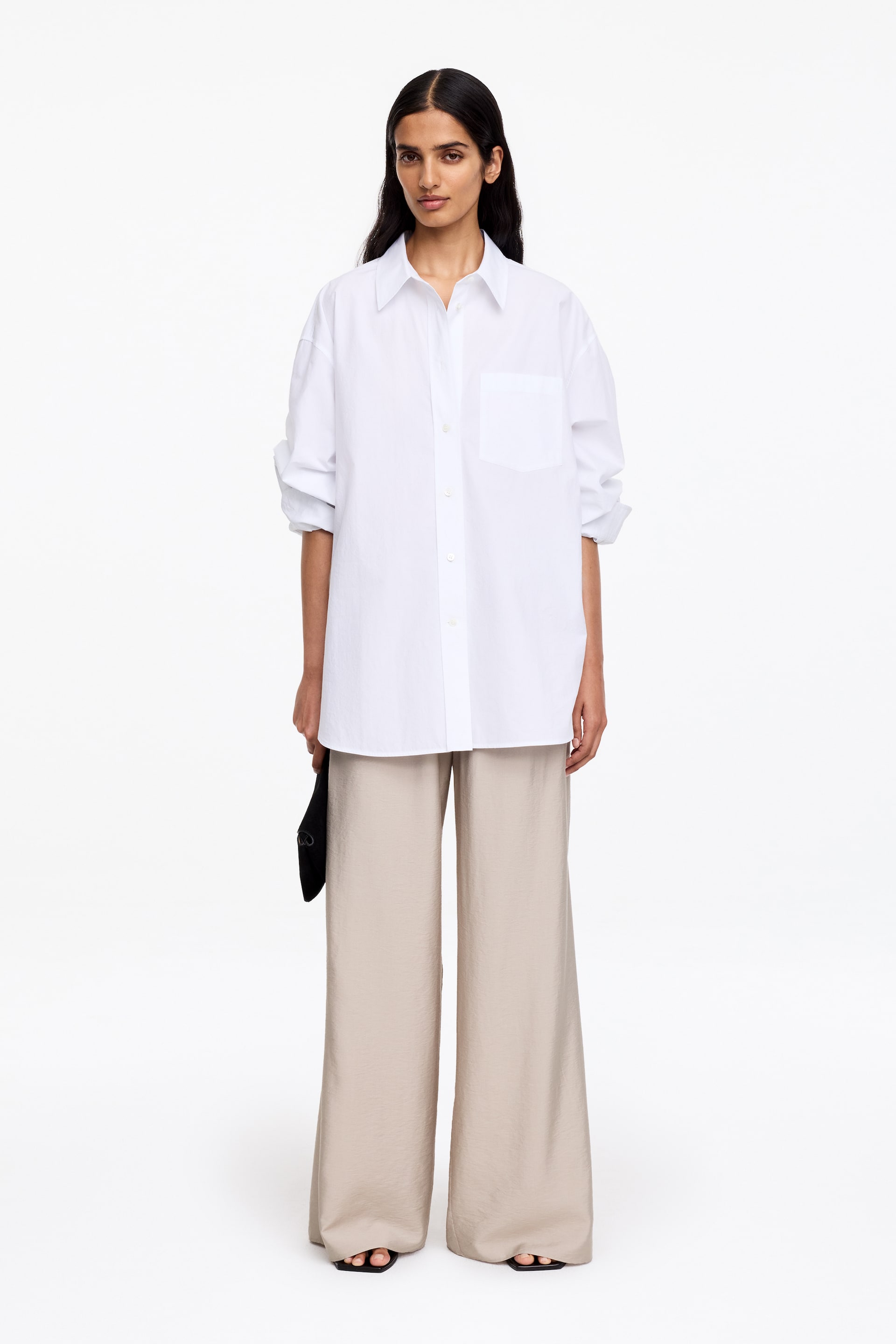 Agrandir l'image: Pantalon beige clair à coupe ample et jambes larges, confectionné dans un tissage lisse et fluide. Le mannequin porte ce pantalon.