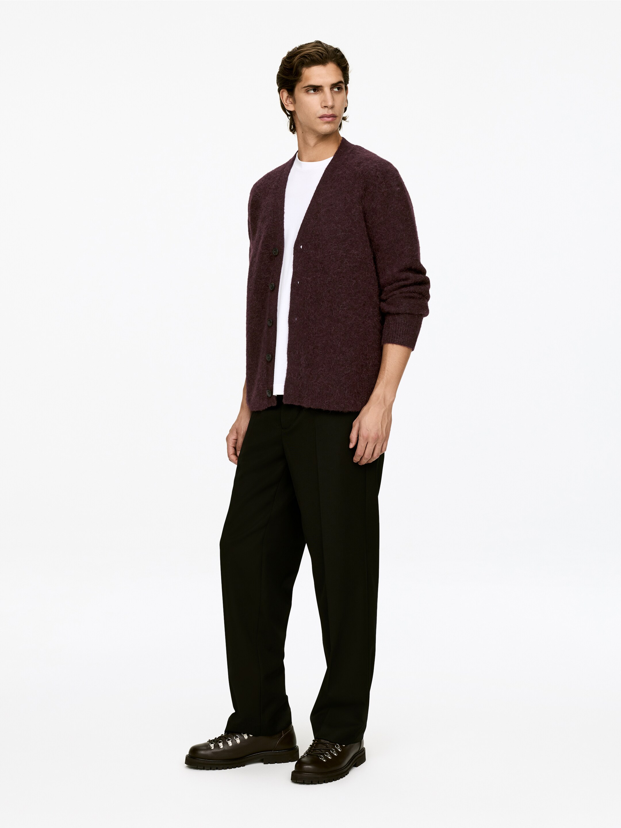 Ver imagem maior: Um cardigan felpudo cor de vinho está a ser apresentado, usado sobre uma t-shirt branca e ligeiramente inclinado para a direita, exibindo um decote em V, um fecho de botões frontais com botões escuros e mangas compridas que terminam em punhos canelados.