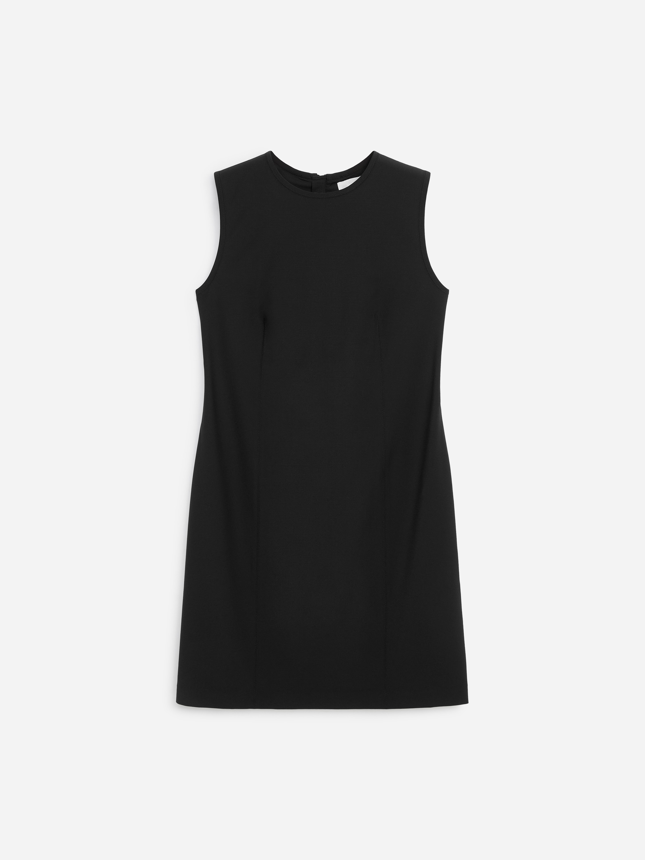 En svart, ärmlös rak klänning med rund halsringning och rak silhuett bärs av modellen. Klänningen stylas med svarta över-knee-läderstövlar och en liten svart axelväska.