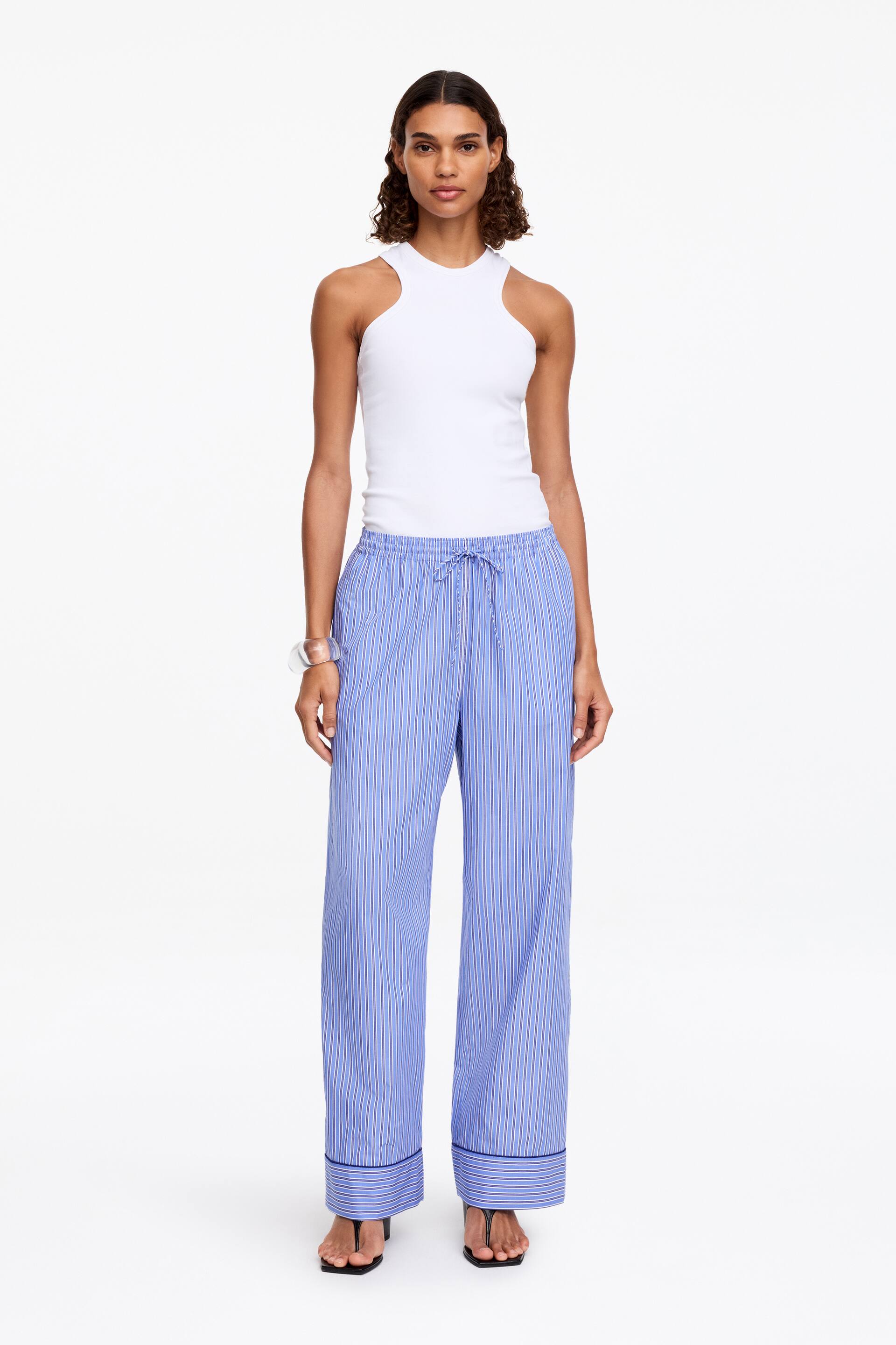 View larger image: Light blue and white striped wide-leg trousers feature a drawstring waist and cuffed hems with navy blue piping.