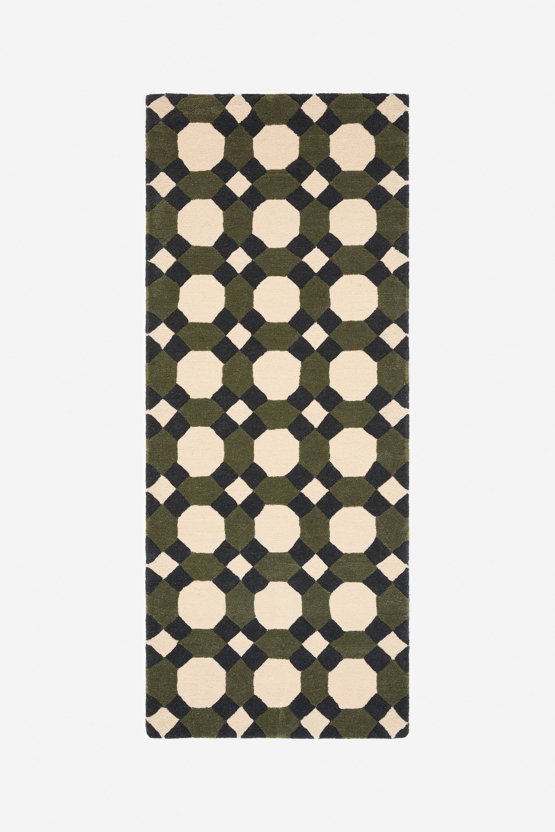 Visualizza immagine più grande: Il tappeto presenta un motivo geometrico ripetuto di ottagoni color crema, ottagoni verde scuro e quadrati grigio scuro. Il tappeto rettangolare è steso in piano, mostrando il suo design completo.